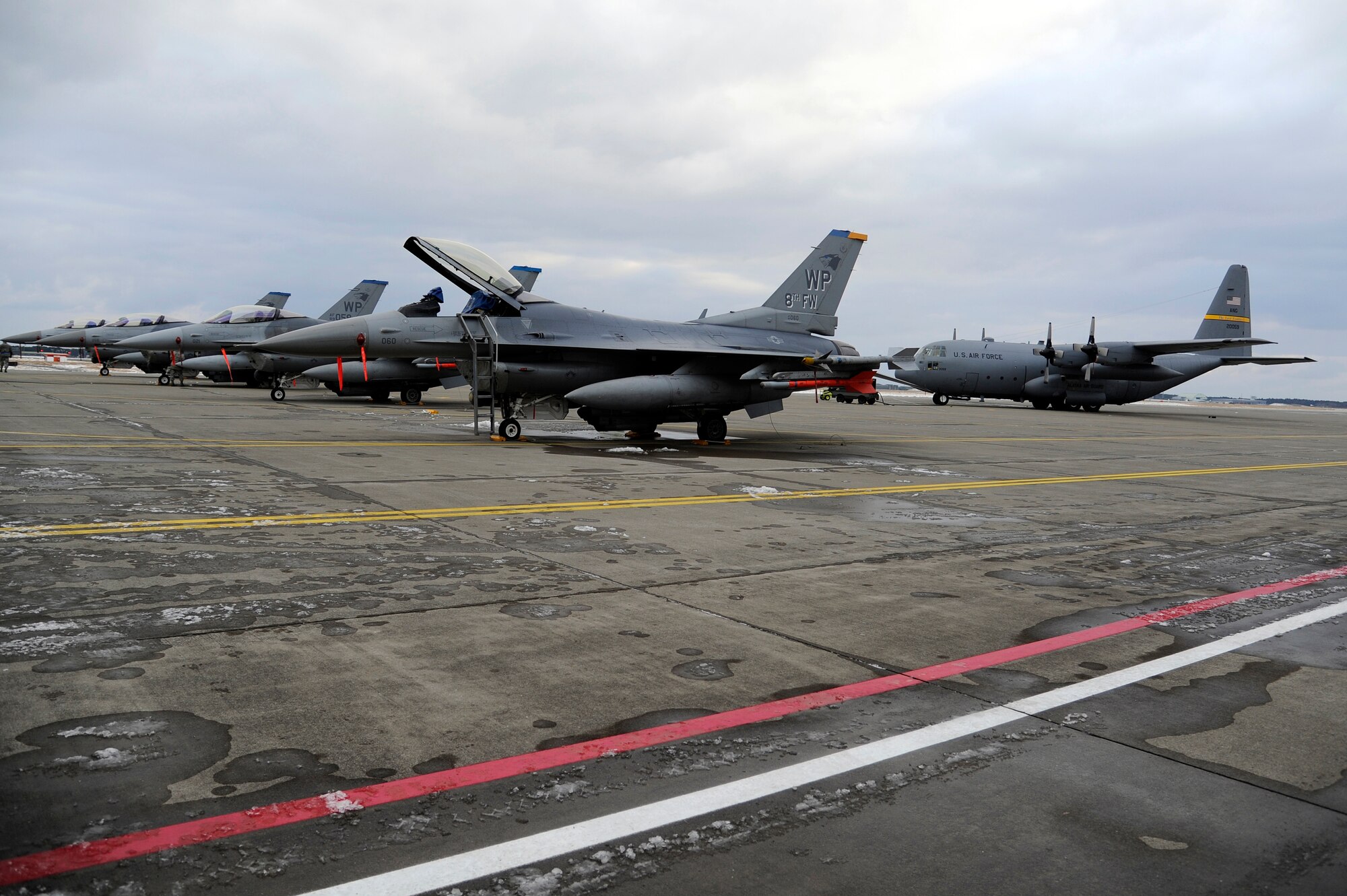 MISAWA AIR BASE, Japan - A C-130 from the Alaska National Guard and eight F-16s with the 35th Fighter Squadron out of Kunsan Air Base, Korea, sit on the flightline awaiting participation as aggressors during an operational readiness inspection here Dec. 6. The 35 FW is currently going through an ORI which occur every two years. The Pacific Air Forces Inspector General Team will spend this week evaluating the deployment capabilities of Misawa's airmen. (U.S. Air Force photo/Tech. Sgt. Marie Brown)
