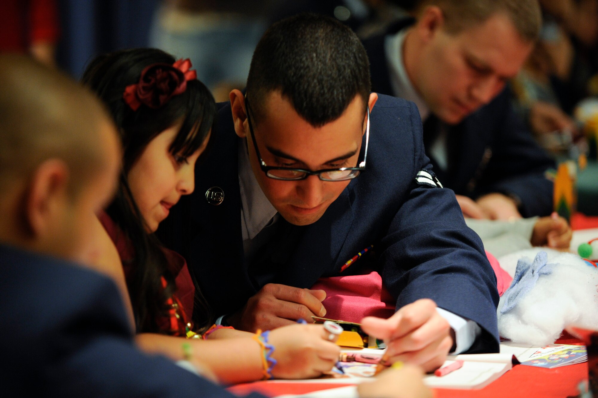 VANDENBERG AIR FORCE BASE, Calif. -- Airman 1st Class Diego Rojas colors with Lizbeth, age 6 from the Lompoc area, while waiting for lunch during Operation Kids Christmas at the Pacific Coast Club here Saturday, Dec. 3, 2011. OKC is an annual event, organized and run by a private organization,  in which approximately 200 local children are brought on base and given the opportunity to play games, meet Santa and enjoy the companionship of volunteer military members. (U.S. Air Force/Staff Sgt. Levi Riendeau)