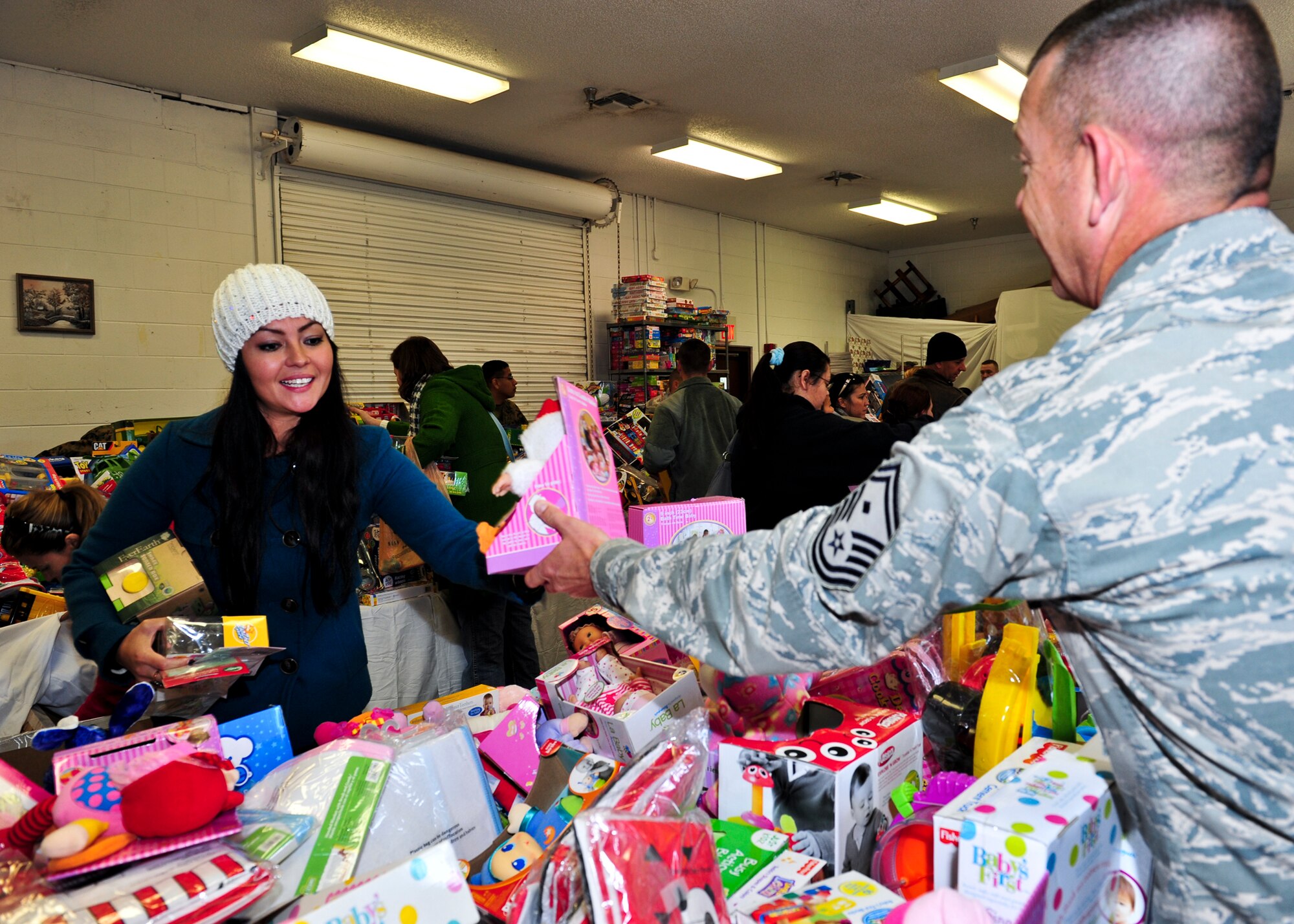 Erika Pinola receives help picking out a toy for her three children from a volunteer at the 8th annual toy distribution Nov. 30 at the Airman’s Attic. Members of all services up to the grade of E-5, lined up to find the perfect gift for their children. More than 4,000 toys were donated for the event, helping more than 200 families in the Eglin community. (U.S. Air Force photo/Sachel Seabrook)