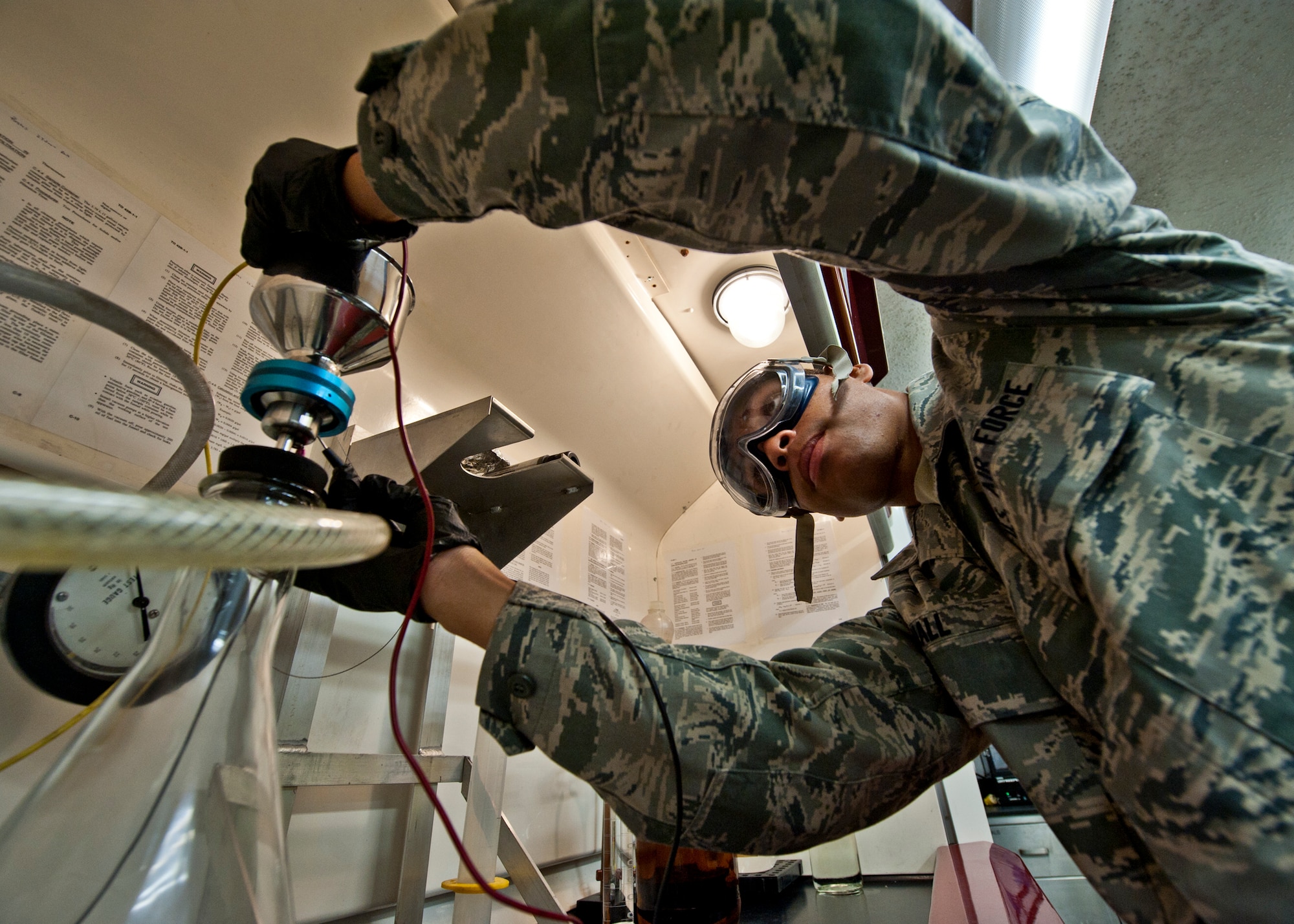 Airman 1st Class Troy Hall, with the 96th Logistics Readiness Squadron, places a funnel onto the filter before pouring in JP-8 fuel.  This test is called the bottle method because a gallon bottle of JP-8 is assessed.  The test evaluates how quickly the JP-8 filters through the mechanism and the amount of sediment that is captured on the filter pad.  (U.S. Air Force photo/Samuel King Jr.)
