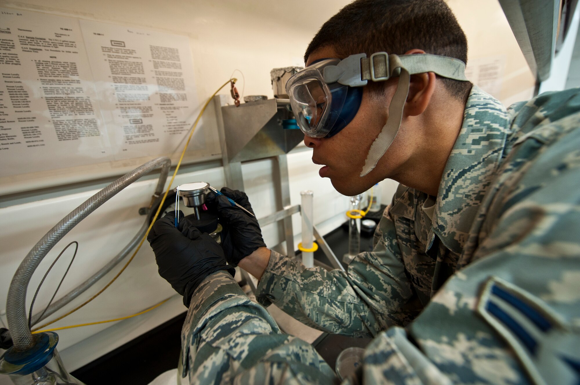 Airman 1st Class Troy Hall, with the 96th Logistics Readiness Squadron, delicately places a pad onto the filter.  The pad is used to gather sediment contained in a gallon of JP-8.  The pad is weighed before and after the fuel is filtered through it.  The difference between the two weights is the amount of solids in the fuel.  The weight needs to be at or below .5 milligrams per liter.  (U.S. Air Force photo/Samuel King Jr.)