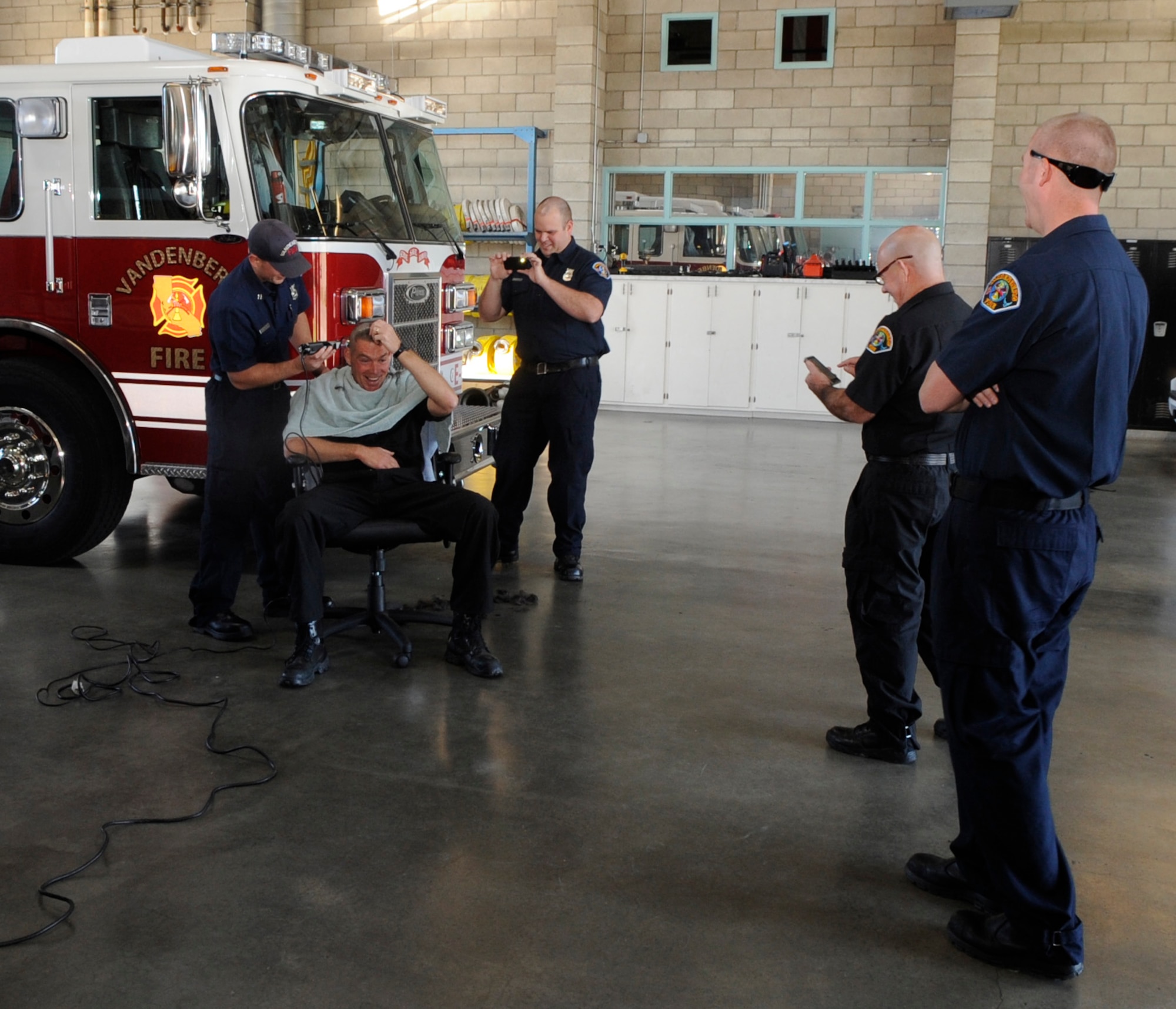 VANDENBERG AIR FORCE BASE, Calif. — Vandenberg Engine 2 captain John Markley, gets his head shaved by a Vandenberg fire rescue truck captain, Emanuel Villegas, while members from the Vandenberg Fire Department watch Wednesday, Nov. 30, 2011.  Members shaved their heads in honor of Ryan Raffel, the 5-year-old nephew of Vandenberg Fire Department firefighter Robert Raffel, who was diagnosed with Leukemia earlier this year.  (U.S. Air Force photo/ Tech. Sgt. Scottie McCord)