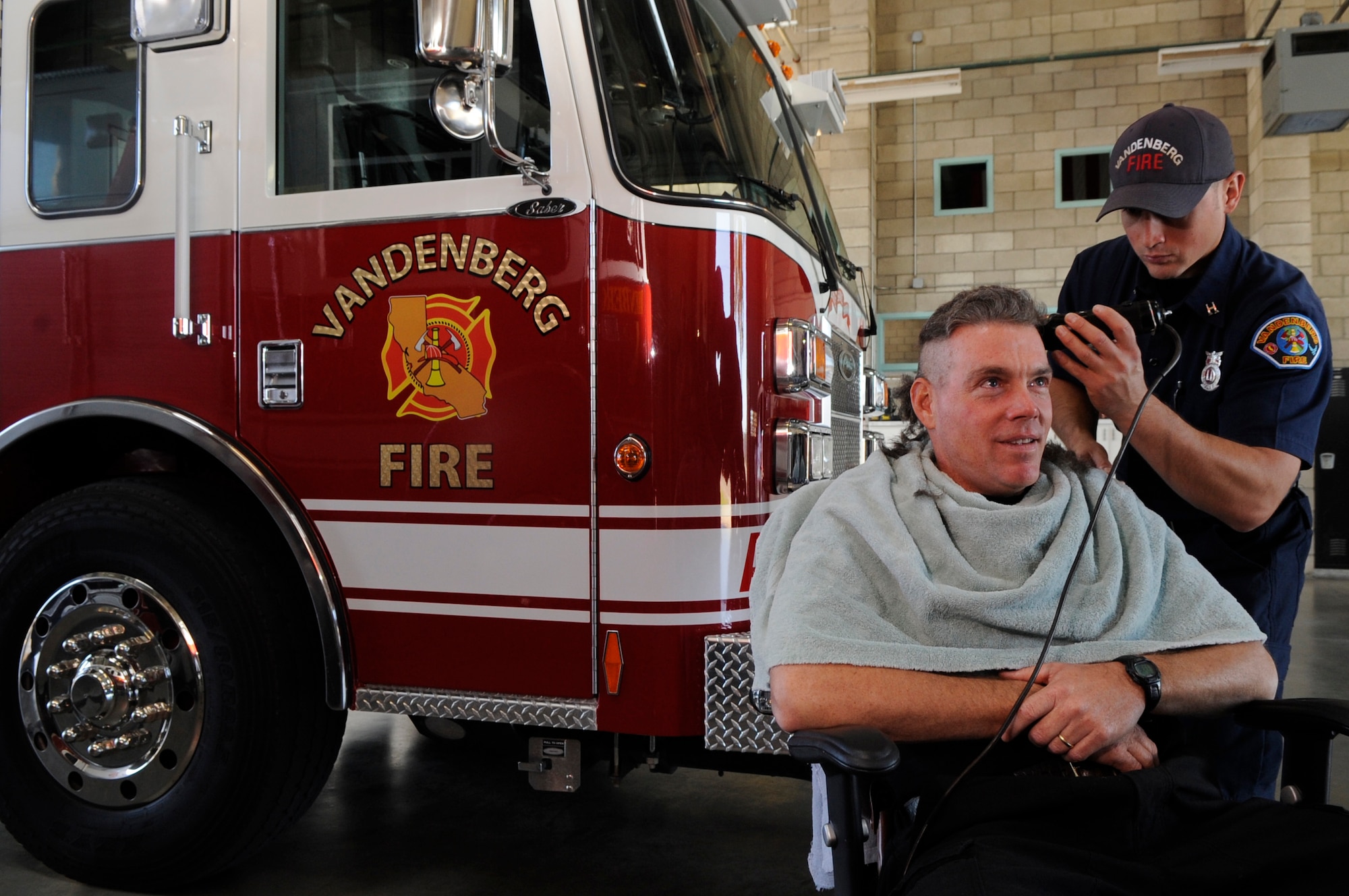 VANDENBERG AIR FORCE BASE, Calif. – Emanuel Villegas, a Vandenberg Fire Department rescue truck captain, shaves the head of John Markley, in honor of Ryan Raffel here Wednesday, Nov. 30, 2011.  Ryan, the 5-year-old nephew of Vandenberg Fire Department firefighter, Robert Raffel, was diagnosed earlier this year with Leukemia. (U.S. Air Force photo/ Tech. Sgt. Scottie McCord)