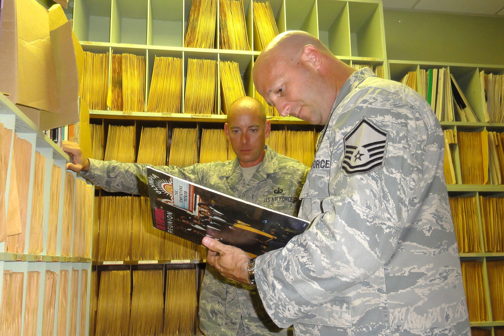 WAKE ISLAND AIRFIELD -- Master Sgt. Jean-Guy Fleury and Master Sgt. John Solane, 611th Detachment 1 contracting quality assurance specialist, look at the back cover of “The Temptations Reunion” album in the old radio room.  There are approximately 9,000 records in the collection, most of which were produced and distributed by the American Force Radio and Television Service. (U.S. Air Force photo/Capt. Amy Hansen)                        