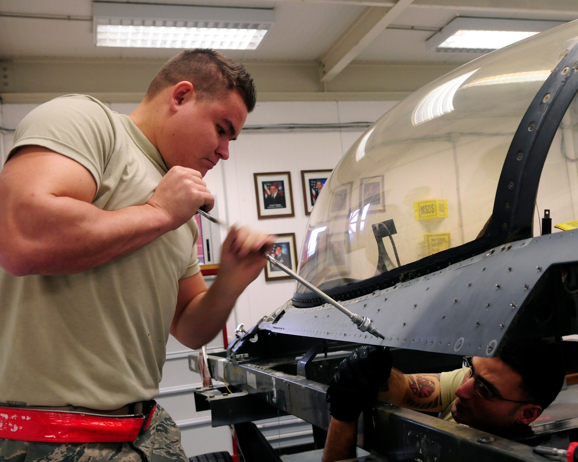 (From Left) Airman 1st Class Justin Fromm aircrew egress systems journeyman and Staff Sgt. Raymond Pantaleo aircrew egress systems craftsman 31st Maintenance Squadron, removes panels from a jet canopy  Dec. 5 at Aviano Air Base, Italy. Aircrew egress systems technicians maintain aircraft egress systems including, ejection seats, canopies, and hatches. (U.S. Air Force photo/Airman 1st Class Briana Jones)