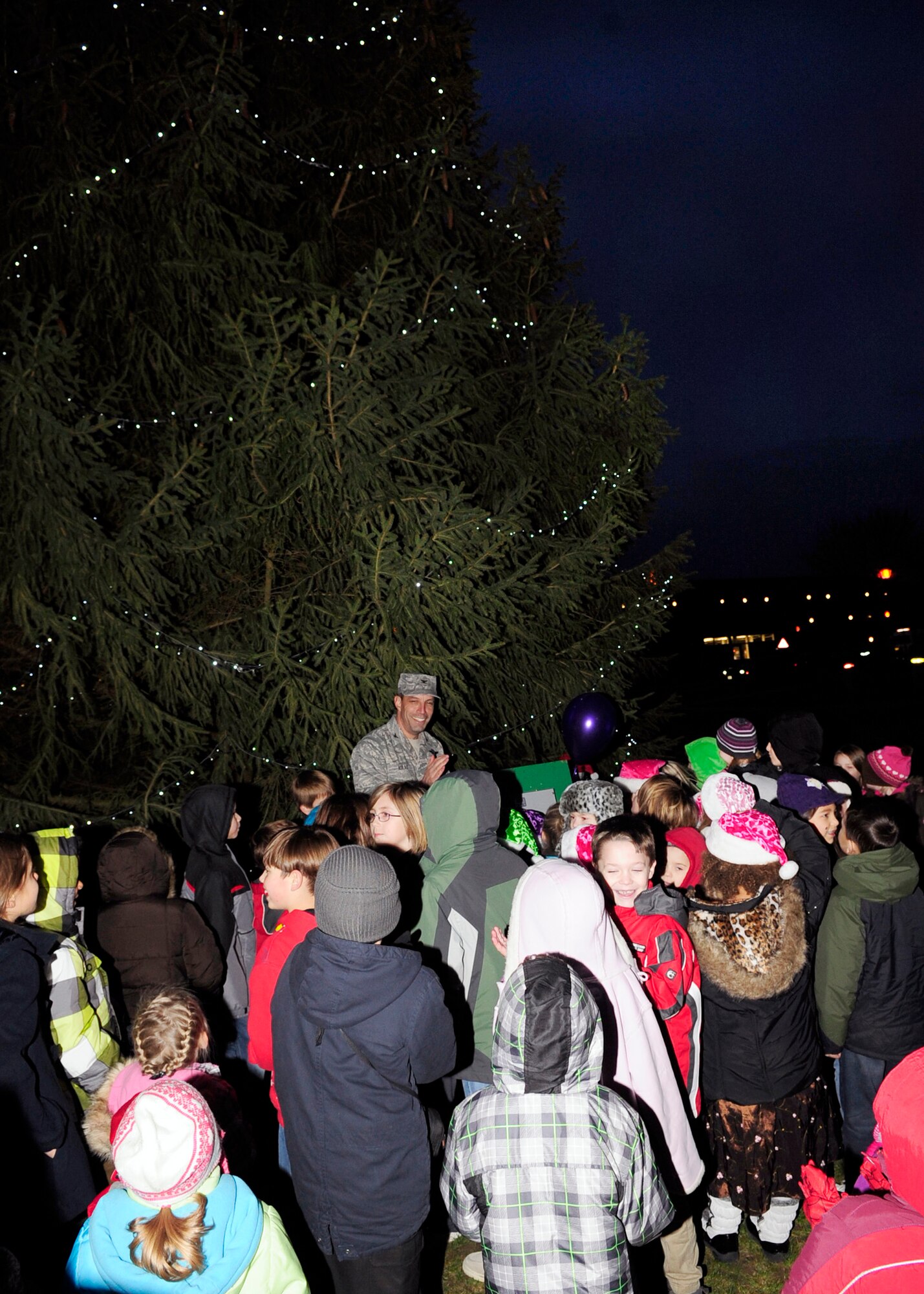 RAF MILDENHALL, England – Col. Christopher Kulas, 100th Air Refueling Wing commander, assisted by children from RAF Mildenhall, flips the switch illuminating the Christmas tree during the base Christmas Tree Lighting Ceremony here Dec. 2, 2011. The event celebrated the beginning of the holiday season for RAF Mildenhall. (U.S. Air Force photo/Senior Airman Ethan Morgan) 