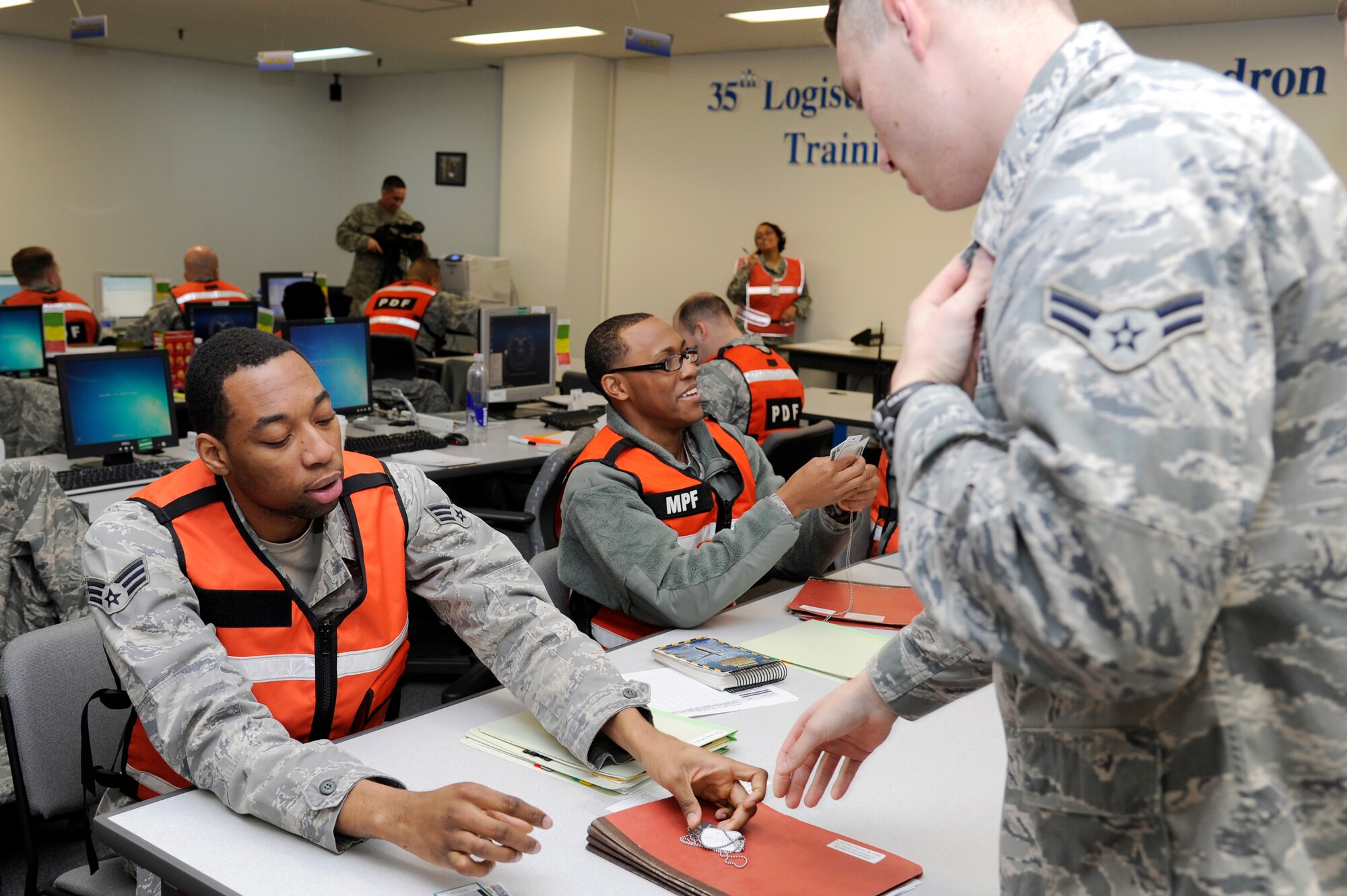 MISAWA AIR BASE, Japan - Senior Airman Dominique Barrett, left, 35th Force Support Squadron, inspects dog tags from Airman 1st Class Alexander Phillips, 35th Maintenance Squadron, during the personnel deployment function line portion of an operational readiness inspection here Dec. 5. The Pacific Air Forces Inspector General team is in town to evaluate the airmen of the 35th Fighter Wing and their ability to deploy. (U.S. Air Force photo/Tech. Sgt. Marie Brown)