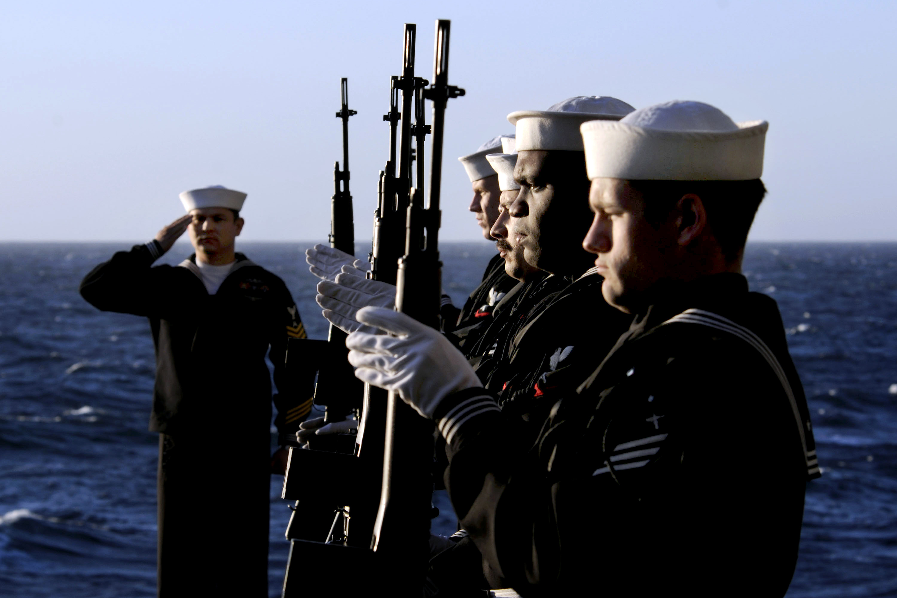 U.S. Navy sailors present arms during a burialatsea ceremony for 20