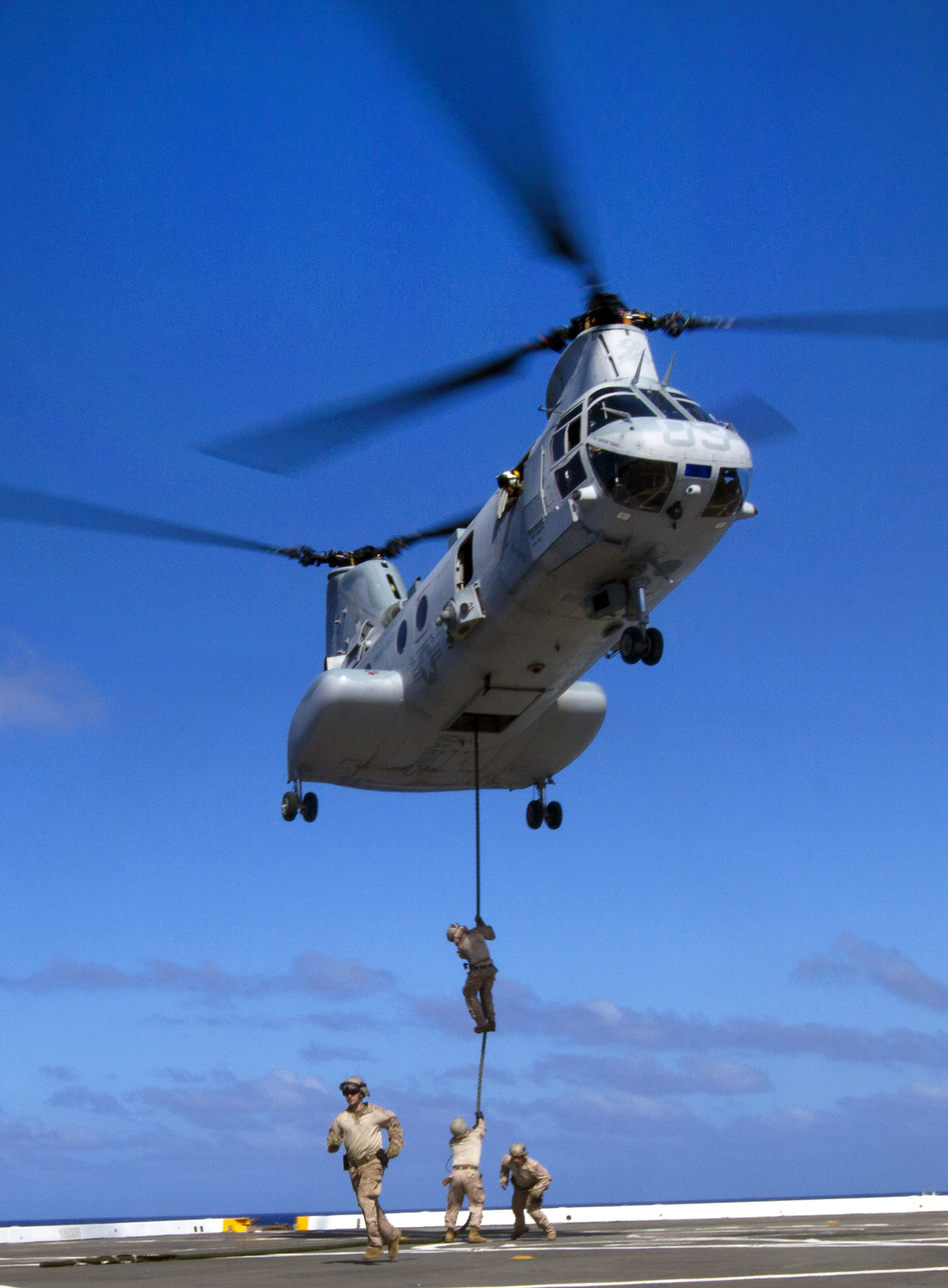 U.S. Marines fast-rope from a CH-46E Sea Knight helicopter onto the flight  deck of