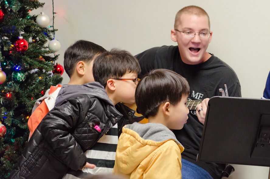 Senior Airman Joseph Cross, 8th Maintenance Squadron fuel systems journeyman, plays the banjo as Ilmagwon Orphanage boys look on during dinner at the base chapel’s SonLight Inn during a Christmas party for the orphans at Kunsan Air Base, Republic of Korea, Dec. 3, 2011. With open arms, 63 Wolf Pack members graciously welcomed the orphans to their home for an afternoon of fun, games, food and presents. (U.S. Air Force photo by Senior Airman Derrick Schwieters/Released)