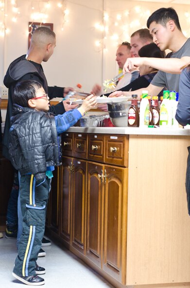 An Ilmagwon Orphanage boy steps up on his toes as he is served dinner at the base chapel’s SonLight Inn during his visit for a Christmas party at Kunsan Air Base, Republic of Korea, Dec. 3, 2011. With open arms, 63 Wolf Pack members graciously welcomed the orphans to their home for an afternoon of fun, games, food and presents. (U.S. Air Force photo by Senior Airman Derrick Schwieters/Released)