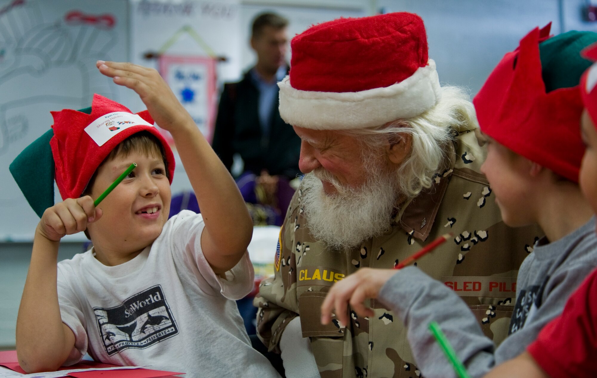 Santa Claus, portrayed by Bud Slade, colors pictures with students from Lomie Heard Elementary School Dec. 2, 2011, on Nellis Air Force Base, Nev. Blue Star Mothers and Santa Claus assisted students as they stuffed stockings and created care packages for their deployed parents.  (U.S Air Force photo by Senior Airman Stephanie Rubi/Released)