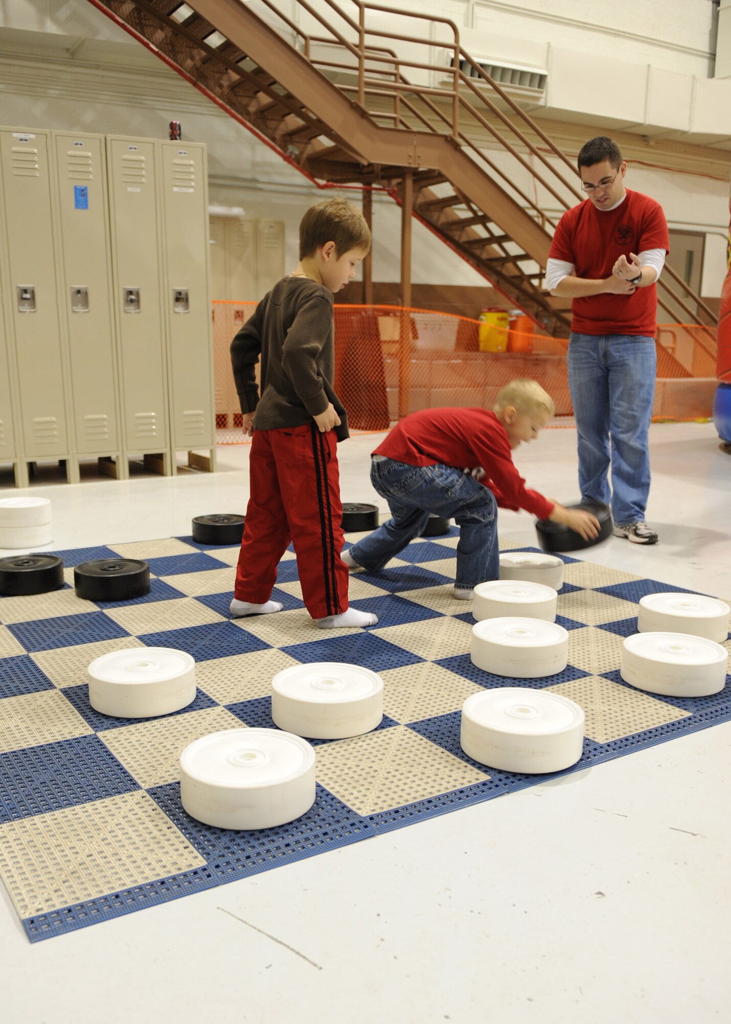 A Team McConnell family plays a game of life-sized chess at a wing children’s holiday party in Hangar 110 Dec. 3, 2011, McConnell Air Force Base, Kan.   Families celebrated the holiday with entertainment including photos with Santa Claus, balloon animals and games.  (U.S. Air Force photo/ Airman 1st Class Maurice Hodges)