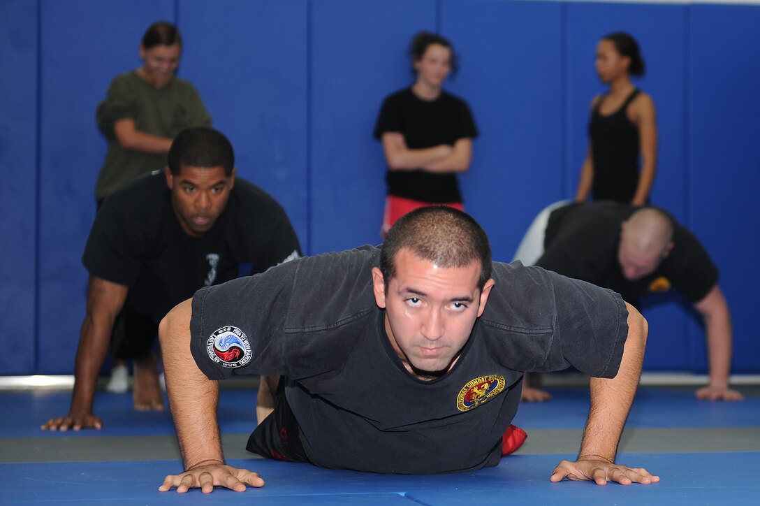 Staff Sgt. Adam Negron, a mixed military combatives instructor, demonstrates maneuvers during the Mixed Military Combatives class at Langley Air Force Base, Va., Dec. 6, 2011. The classes are beginner-friendly, opening with basic instruction, and participants use protective gear to stay safe during the sessions. (U.S. Air Force photo by Staff Sgt. Antoinette Gibson/Released)