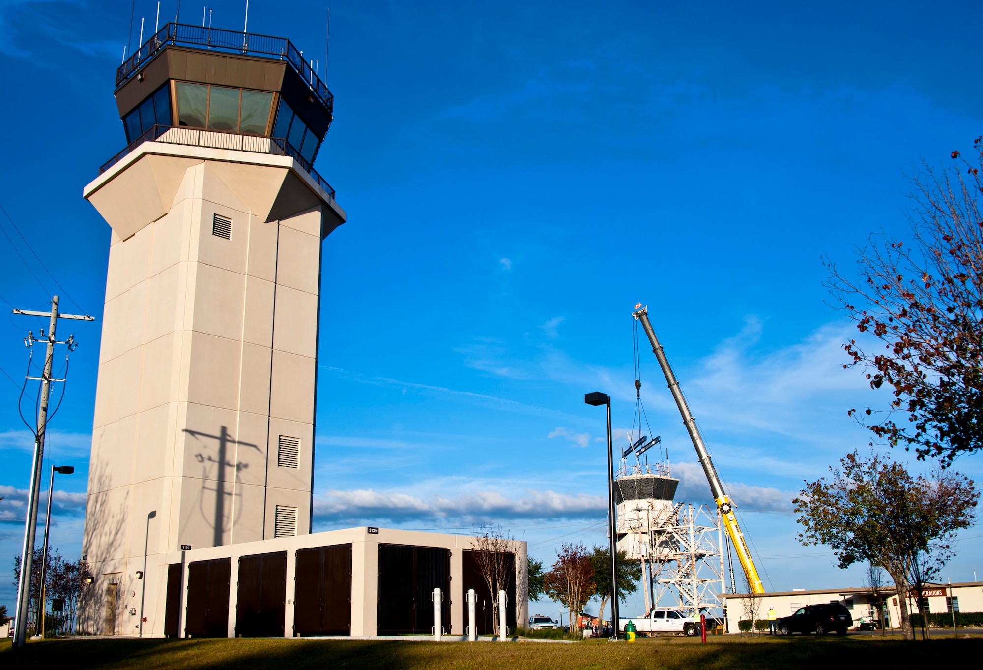 Just behind its new tower, Duke Field’s old air traffic control tower is lowered to the ground Dec. 3. The tower, managed by the 46th Test Wing, was continuously used in guiding in aircraft at Duke Field since the 1950s.  (U.S. Air Force photo/Samuel King Jr.)