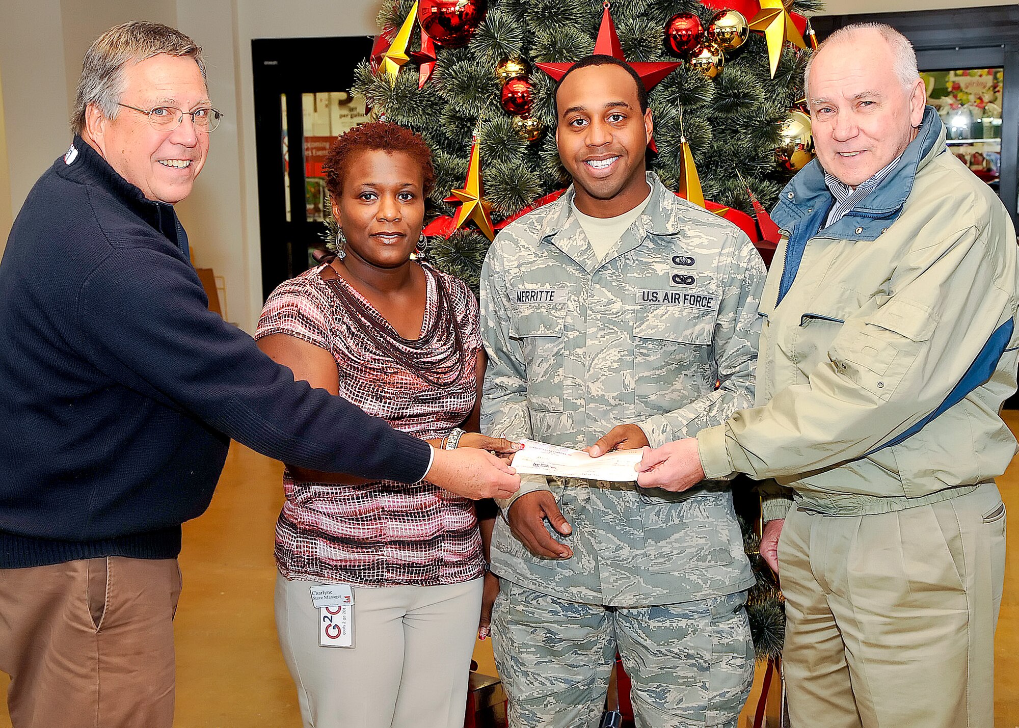 Ben Dawson and Ron Edelmann with the Ocean City Lions Club present Staff Sgt. Javon Merritte, chaplain’s assistant with the 436th Airlift Wing, and Charlyne Morganfield, store manager of the Base Exchange, with a $25,000 check Dec. 1, 2011, at Dover Air Force Base, Del. This is the seventh year that the money has been raised and donated to the Landstuhl Regional Medical Center, Germany, for injured service members. The funds are dispersed by the chief chaplain’s office in the form of $1,000 gift cards. (U.S. Air Force photo by Tech. Sgt. Chuck Walker)