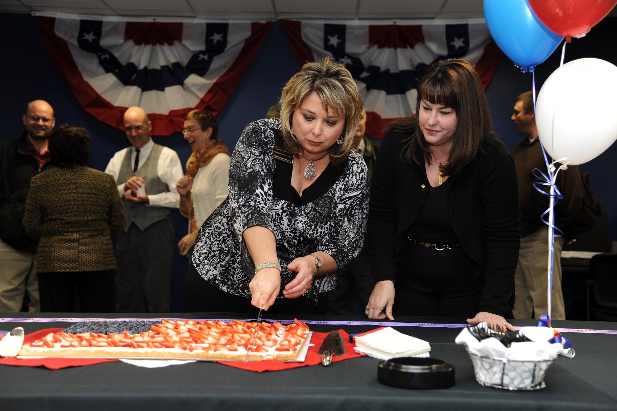 Delilah Nichols (left), director of University of Central Missouri Veterans Services, and Christie Eckfeld, wife of 442nd Fighter Wing vice commander Col. Gregory Eckfeld, cut a cake during a ribbon-cutting ceremony at the UCM Veterans Services Center, Dec. 6, 2011. The center is designed to help servicemembers and dependents more easily pursue a college degree. Col. Alan Teauseau, 442nd Mission Support Group commander, presented a plaque for the center with an A-10 Thunderbolt II 30 mm bullet on behalf of the 442nd Fighter Wing, Whiteman Air Force Base, Mo. The wing is an Air Force Reserve unit. (U.S. Air Force photo/Staff Sgt. Lauren Padden)