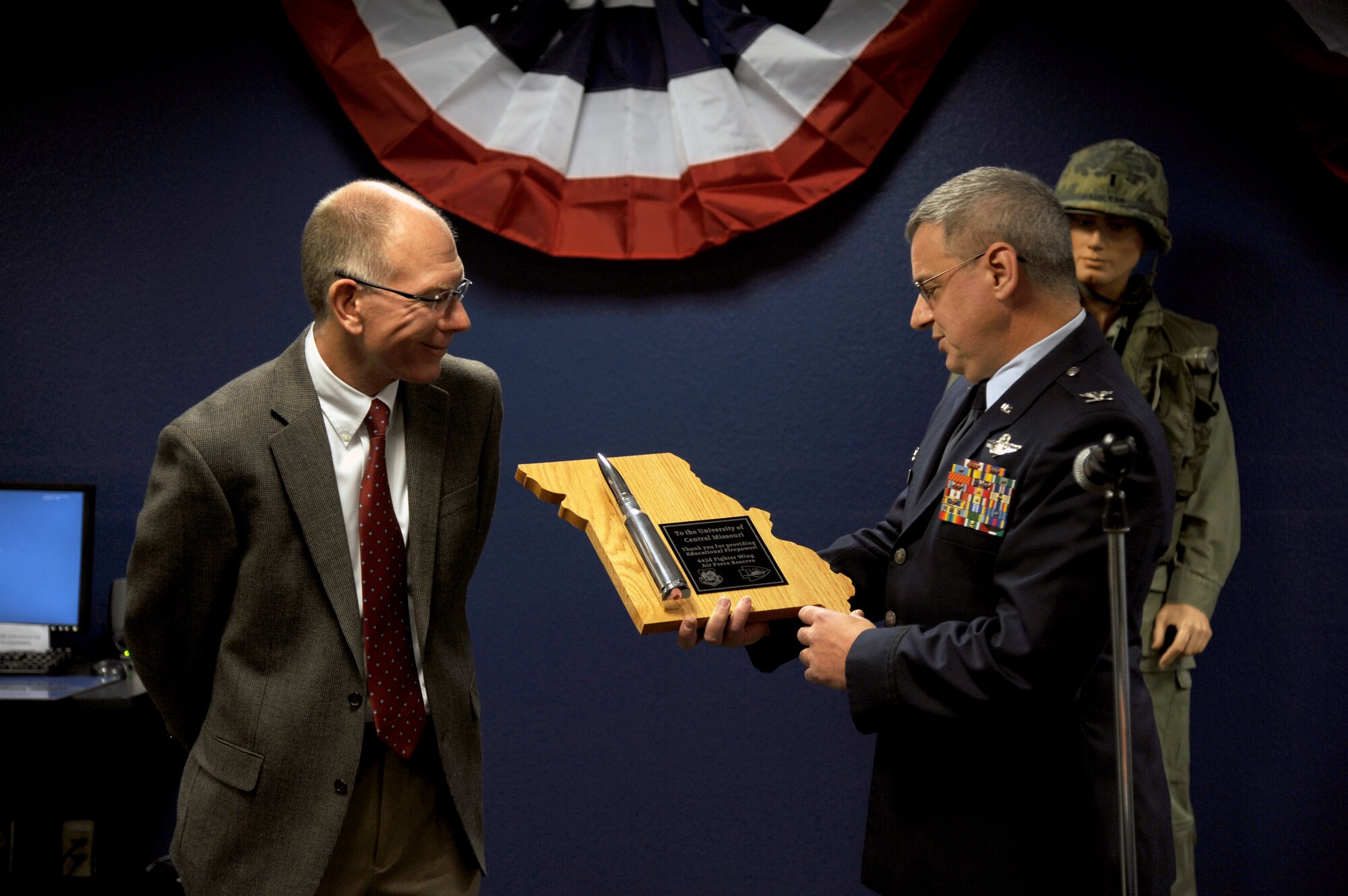 Col. Alan Teauseau (right), 442nd Mission Support Group commander, presents a plaque with an A-10 Thunderbolt II 30 mm bullet to Dr. Charles Ambrose, University of Central Missouri president, during a ribbon-cutting ceremony at the UCM Veterans Services Center, Dec. 6, 2011. The center is designed to help servicemembers and dependents more easily pursue a college degree. The 442nd MSG is part of the 442nd Fighter Wing, an A-10 Thunderbolt II Air Force Reserve unit at Whiteman Air Force Base, Mo. (U.S. Air Force photo/Staff Sgt. Lauren Padden)
