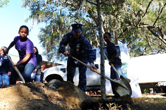 Master Chief Petty Officer Billy Cady helps students plant a tree for Arbor Day at Hunley Park Elementary School Dec. 2. This is the 16th year JB Charleston has been a member of the Tree City USA foundation. To become a Tree City USA member, a community most meet four annual standards:  a tree protection board or manager, a tree care ordinance, a comprehensive community forestry program and an Arbor Day observance.  Cady is the JB Charleston - Weapons Station command master chief.  (U.S. Air Force photo/ Staff Sgt. Nicole Mickle)