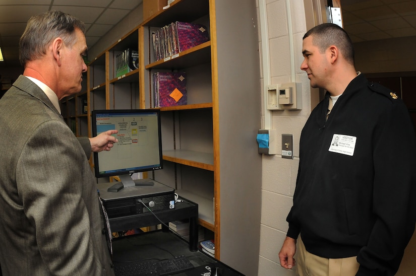 Robert Bohnstengel,  James Island Charter High School principal, shows Chief Petty Officer Michael Vira one of their ‘showcase’ programs called the Tardy-Sweep during the national “Principal for a Day” event hosted by The Education Foundation Dec. 1. Chief Vira is the food service officer at the Joint Base Charleston-Weapons Station’s Galley. (U.S. Navy photo/Petty Officer 1st Class  Jennifer Hudson)