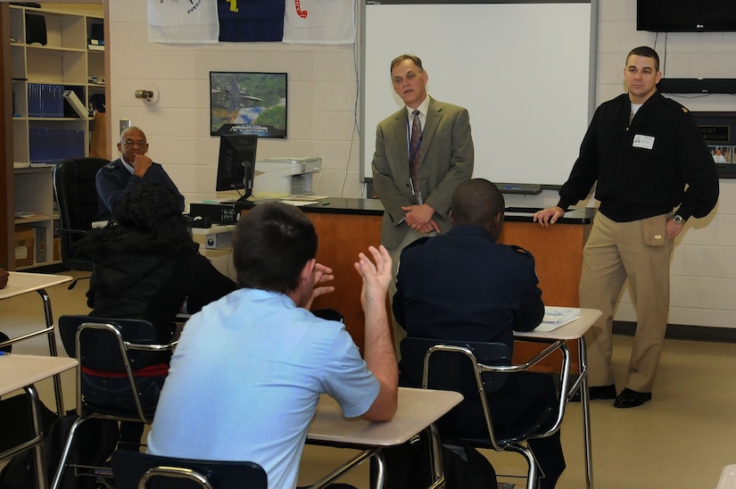 Robert Bohnstengel , James Island Charter High School principal (center) and Chief Petty Officer Michael Vira visit the school’s Air Force Reserve Officer Training Corps classroom to talk to students about future plans and their classroom assignments during the national “Principal for a Day” event hosted by The Education Foundation  Dec. 1. Vira is a food service officer at the Joint Base Charleston-Weapons Station’s Galley. (U.S. Navy photo/Petty Officer 1st Class Jennifer Hudson)