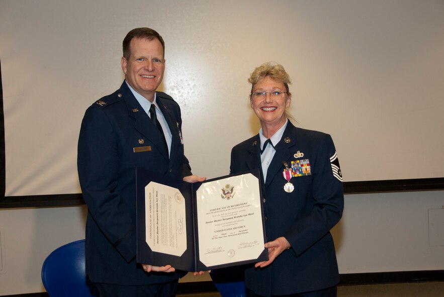 Col. Mick McGuire, 162nd Fighter Wing commander, presents Senior Master Sgt. Brenda Chase with her retirement certificate Dec. 3 after 37 years of service. (U.S. Air Force photo/Master Sgt. Dave Dave Neve)