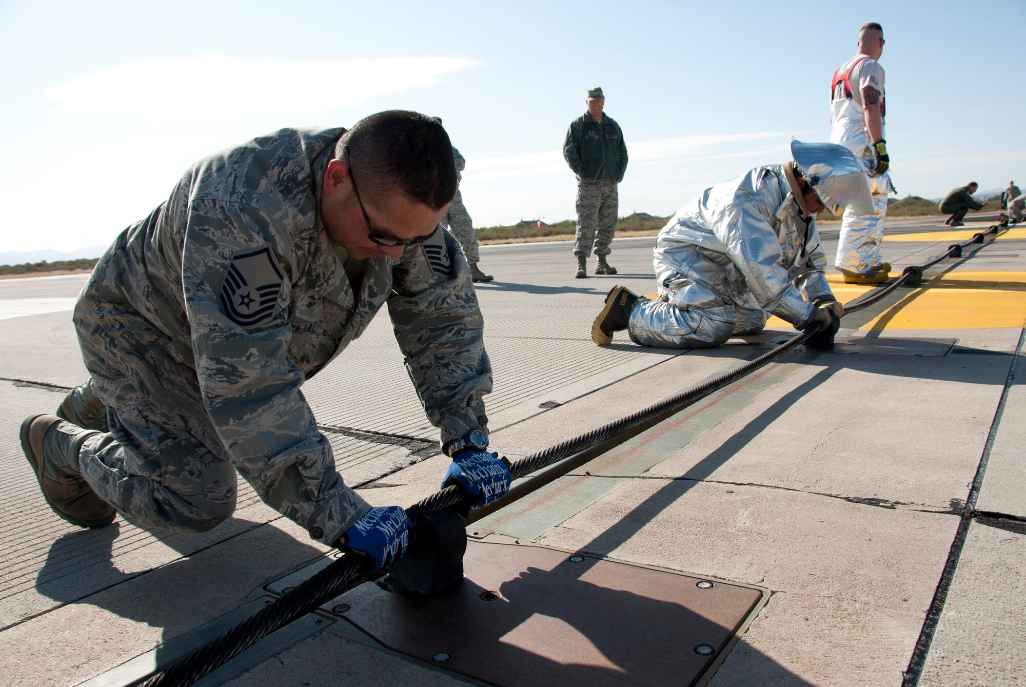 Master Sgt. Osbaldo Carbajal, 162nd Civil Engineer Squadron, reinstalls the barrier catch cable on the Tucson International Airport runway after it was tested Dec. 3. (U.S. Air Force photo/Master Sgt. Dave Dave Neve)