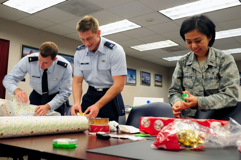 U.S. Air Force 1st Lt. Maira Malhabour, 633rd Medical Support Squadron laboratory services element chief, Capt. Tyler Johnson, Electronic Systems Center deputy director air operation center 10.1, and 2nd Lt. Ben Brown, Air Combat Command A8 Training Requirement chief air combat systems, wrap presents donated to the Angel Tree Program at Langley Air Force Base, Va., Dec. 5, 2011. Individuals use the Angel Tree to pick tags that have underprivileged children’s wish lists on them and purchase the gifts for the children.  (U.S. Air Force photo by Airman 1st Class Kayla Newman/Released)