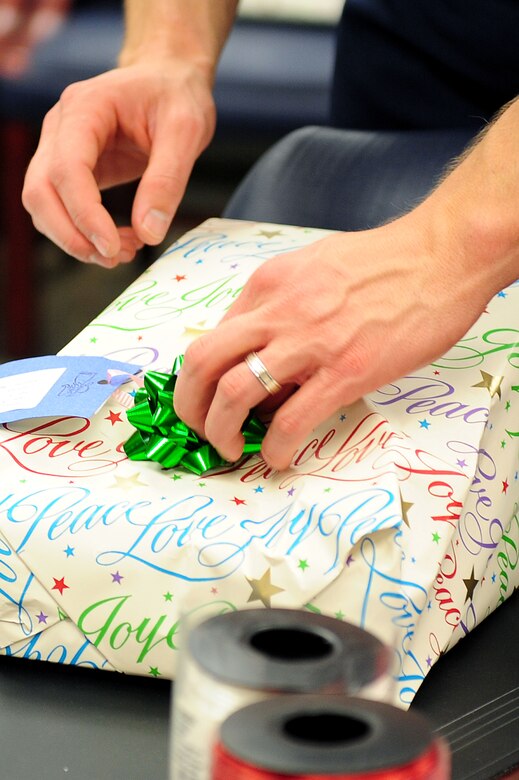 U.S. Air Force Capt. Tyler Johnson, Electronic Systems Center deputy director air operation center 10.1, places a bow on a gift during the Angel Tree Wrapping party at Langley Air Force Base, Va., Dec. 5, 2011. The Angel Tree displays tags that contain underprivileged children’s wish lists for the Holidays; gifts will be shipped Dec. 16, 2011.  (U.S. Air Force photo by Airman 1st Class Kayla Newman/Released)