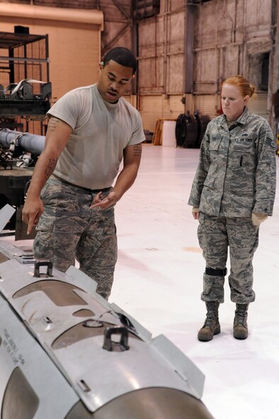 Staff Sgt. Dawn Cox, 4th Aircraft Maintenance Squadron (AMXS) standardization load crew member, observes Airman 1st Class James Wilson inspecting an item on an inert GBU-31 bomb during a minimum proficiency requirement load refresher on Seymour Johnson Air Force Base, N.C., Nov. 30, 2011. Load crew members are not allowed to use technical orders during inspections to ensure they have memorized the information. Cox hails from Collegeville, Pa. Wilson is a 4 AMXS armament system apprentice and hails from Sacramento, Calif. (U.S. Air Force photo by Senior Airman Whitney Stanfield)  
