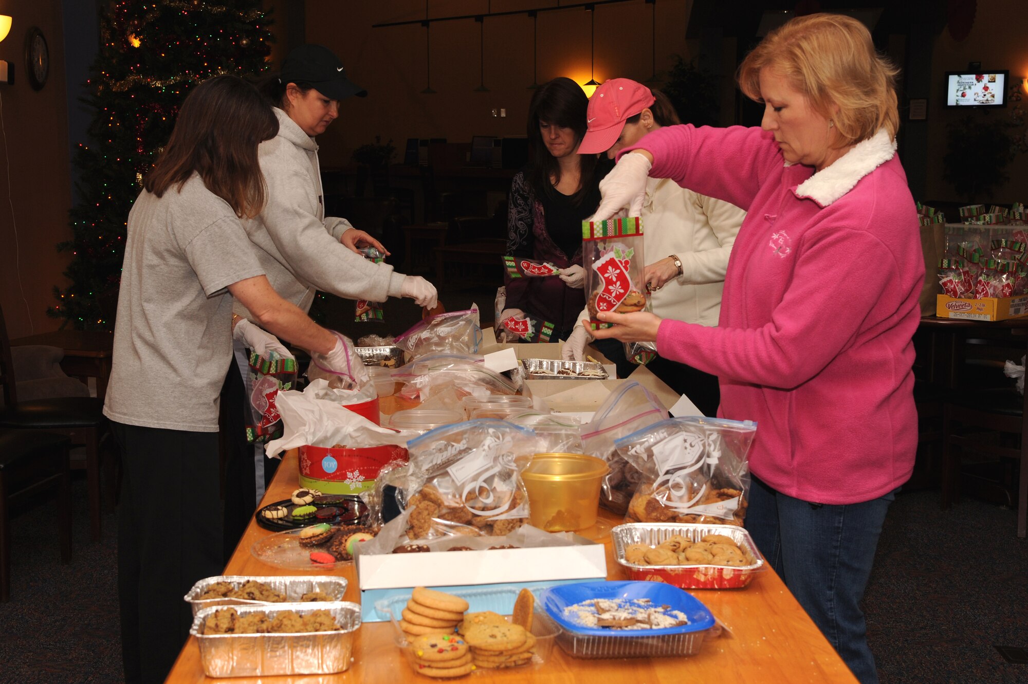 Military spouses volunteer packaging cookies at the Community Activity Center on Dec. 5 at Grand Forks Air Force Base, N.D.  Every year base volunteers surprise the Airmen who live in the dorms with a taste of the upcoming holiday to boost their morale.  (US Air Force photo by Airman 1st Class Xavier Navarro)