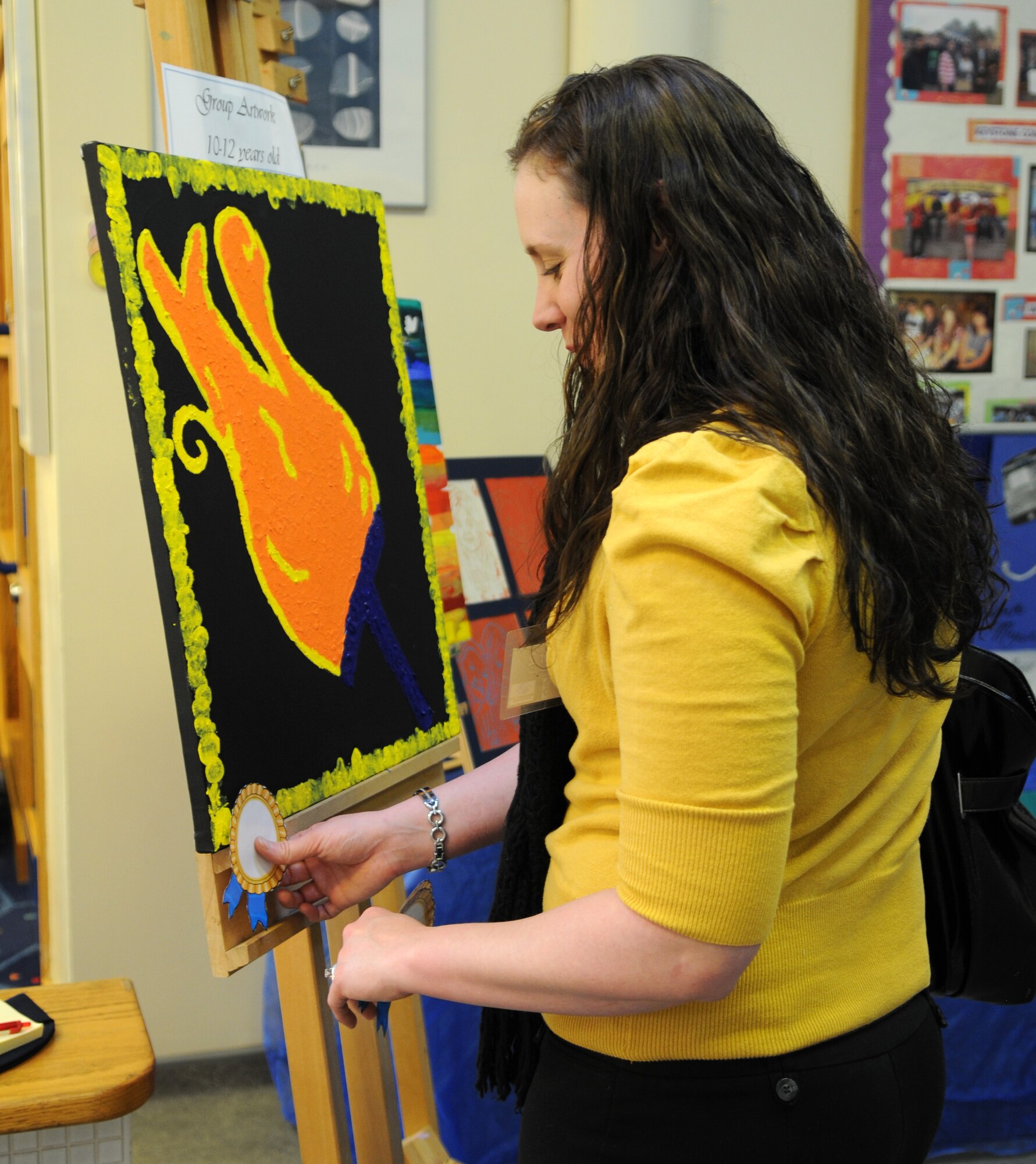 RAF MILDENHALL, England – Jessica Gray, 100th Force Support Squadron Arts and Craft Center employee, awards a ribbon to the best group project, 10 to 12-year-old category, during judging of the Boys & Girls Club of America 2012 National Fine Arts Exhibit at the youth center here, Dec. 5, 2011. The winning entries will be sent to Ramstein Air Base, Germany to compete at the regional level.  Regional winners will then be sent to the BGCA’s national headquarters to compete at the BGCA National Fine Arts Exhibit in Atlanta. (U.S.  Air Force photo/Senior Airman Jerilyn Quintanilla) 