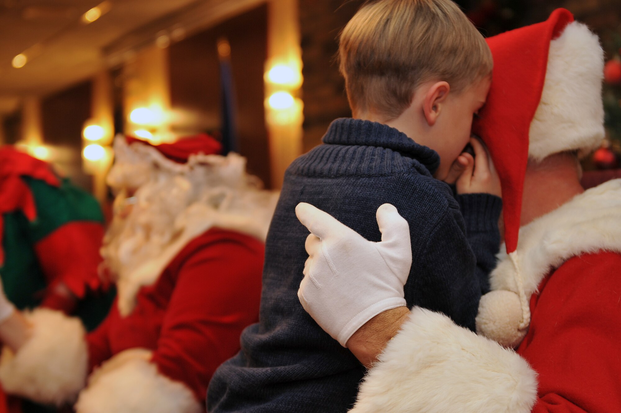 Harper Kean, son of 2nd Lt. Christopher Kean, Air Combat Command Training Support Squadron, whispers to Santa his wishes for Christmas. Team Offutt members and their families watched a tree lighting ceremony followed by holiday activities at the Community Activity Center. (Air Force photo by Jeff Gates)