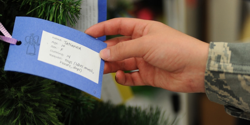U.S. Air Force Airman 1st Class Emily Birchem, 30th Intelligence Squadron geospacial intelligence analyst, reads a wish list tag for an underprivileged child placed on the Langley Angel Tree at Langley Air Force Base, Va., Dec. 5, 2011. Individuals can pick a wish list ornament from the tree and purchase gifts for children who might otherwise go without. (U.S. Air Force photo by Airman 1st Class Teresa Cleveland/Released)