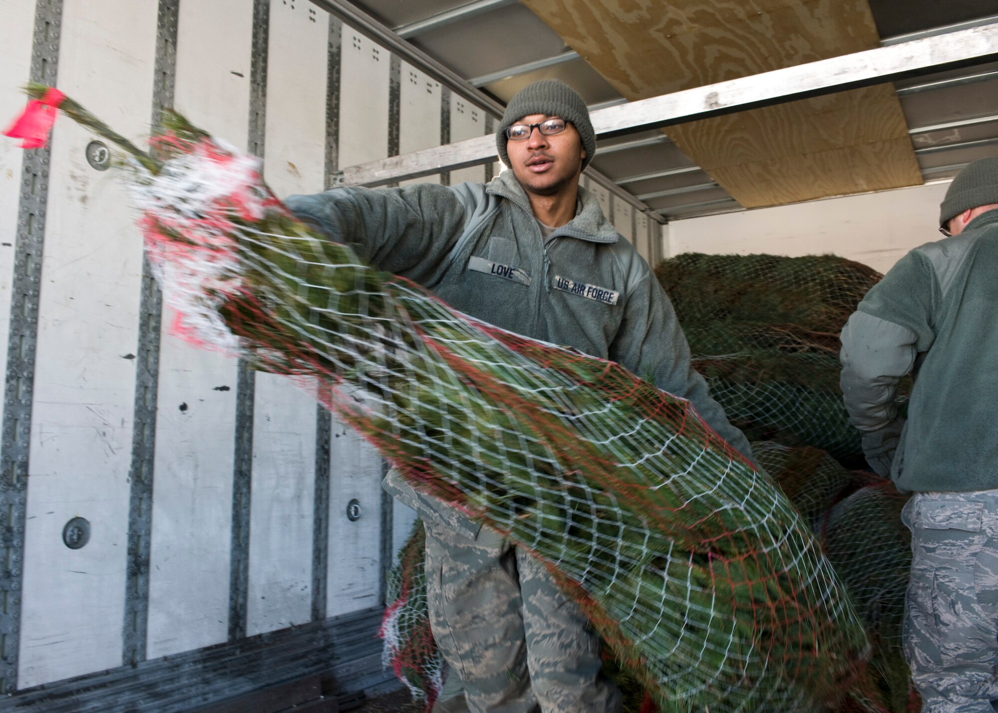 Airman Kristopher Love, 28th Aircraft Maintenance Squadron crew chief, unloads a tree from a truck trailer on Ellsworth Air Force Base, S.D., Dec. 1, 2011. Airmen gathered at the 28th Force Support Squadron Outdoor Recreation office to help unload more than 300 Christmas trees for families on Ellsworth donated by Trees for Troops. (U.S. Air Force photo by Airman Alystria Maurer/Released)