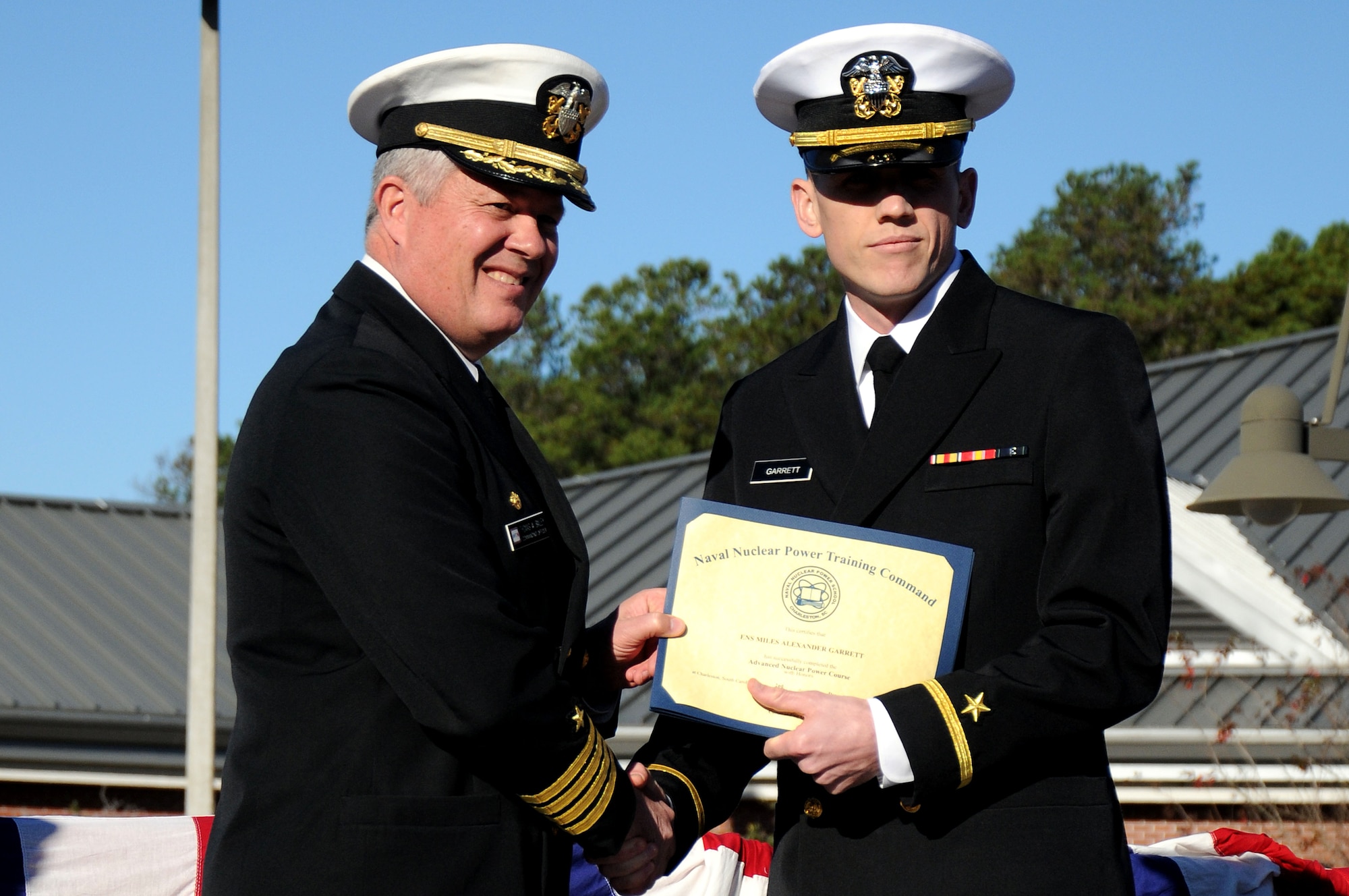 Ensign Miles Garrett receives the Vice Adm. Behrens award from Capt. Thomas Bailey during the Naval Nuclear Power Training Command graduation ceremony for class 1105 at Joint Base Charleston - Weapons Station Dec. 2. The Behrens award recognizes the graduating officer with the highest grade-point average. Garrett earned an overall GPA of 3.76. Bailey is the NNPTC commanding officer. (U.S. Navy photo/Petty Officer 2nd Class Brannon Deugan)
