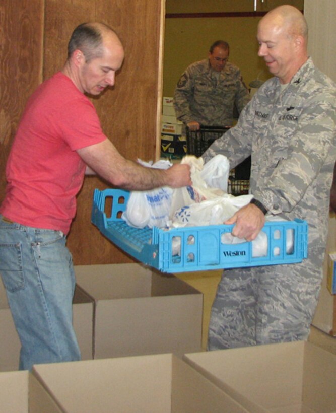 Master Sgt. John Mills (civilian clothes) and Col. John Bartholf, EADS Commander, load boxes with food during the Rome Rescue Mission's Thanksgiving basket project. EADS volunteers put together 250 boxes for delivery to local families and another 250 individual meals that were served at the Mission. 