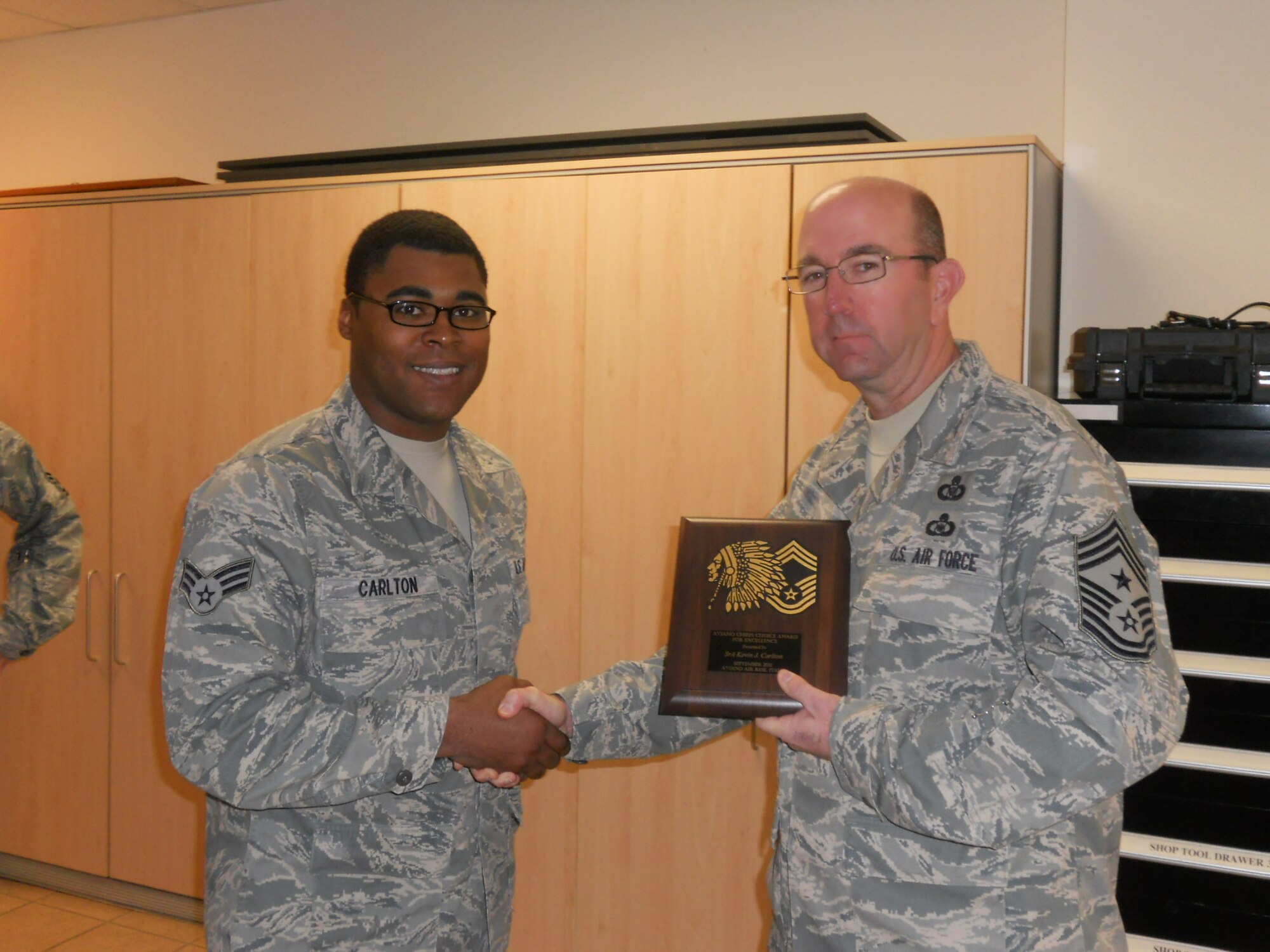 Senior Airman Kevin Carlton, 31st Communications Squadron, receives the Aviano Chiefs' Choice Award for October from the Aviano Chiefs' Group. Aviano chiefs present the Chiefs' Choice Award monthly to an Airman who clearly exceeds Air Force Standards in the areas of dress and appearance, military bearing and exceptional behavior in performance of their duties and in relationships with others. (Courtesy photo)