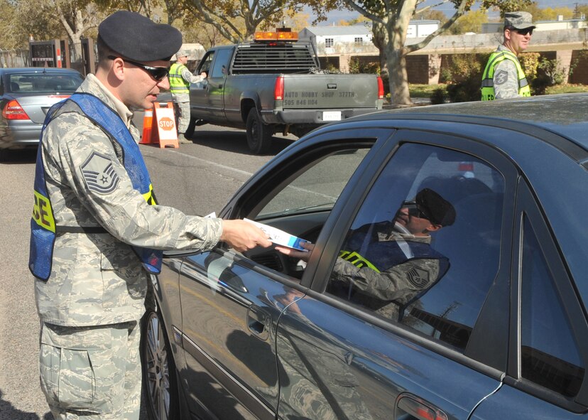 Master Sgt. Cody Green, 377th Security Forces Squadron, passes out pamphlets Tuesday at Kirtland Air Force Base explaining the importance of seat belt use and dangers of cell phone use without a hands-free device while driving.  U.S. Air Force Photo by Todd Berenger.