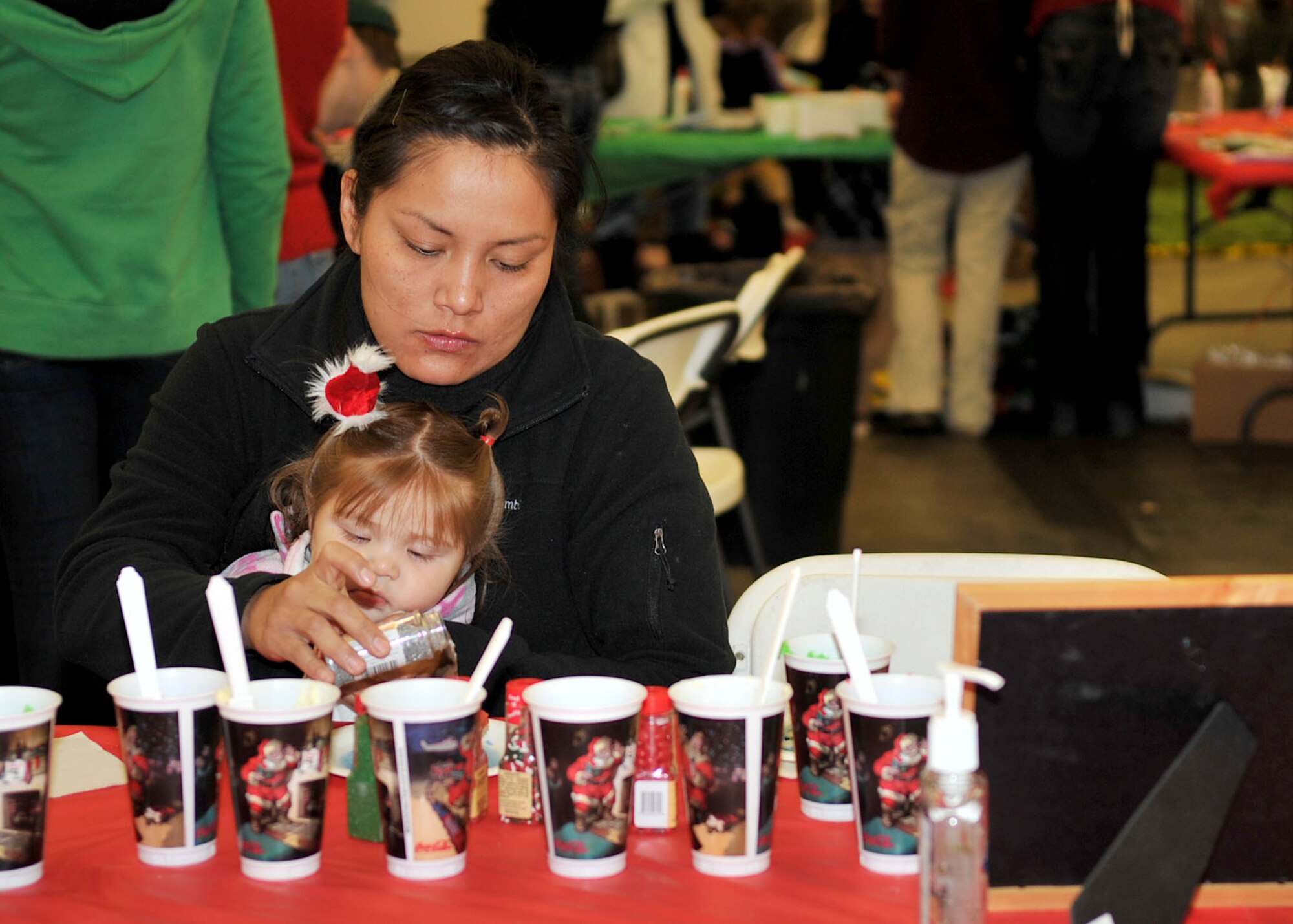RAF MILDENHALL, England – Jennifer Ahboah and daughter Jaime, 8 months, decorate cupcakes at one of the activity corners during the third annual Breakfast with Santa event at the fire department here Dec. 3, 2011. In addition to cupcake decorating, face painting, a story corner, bouncy castles and arts and crafts were also available for the children. (U.S. Air Force photo/Senior Airman Jerilyn Quintanilla)