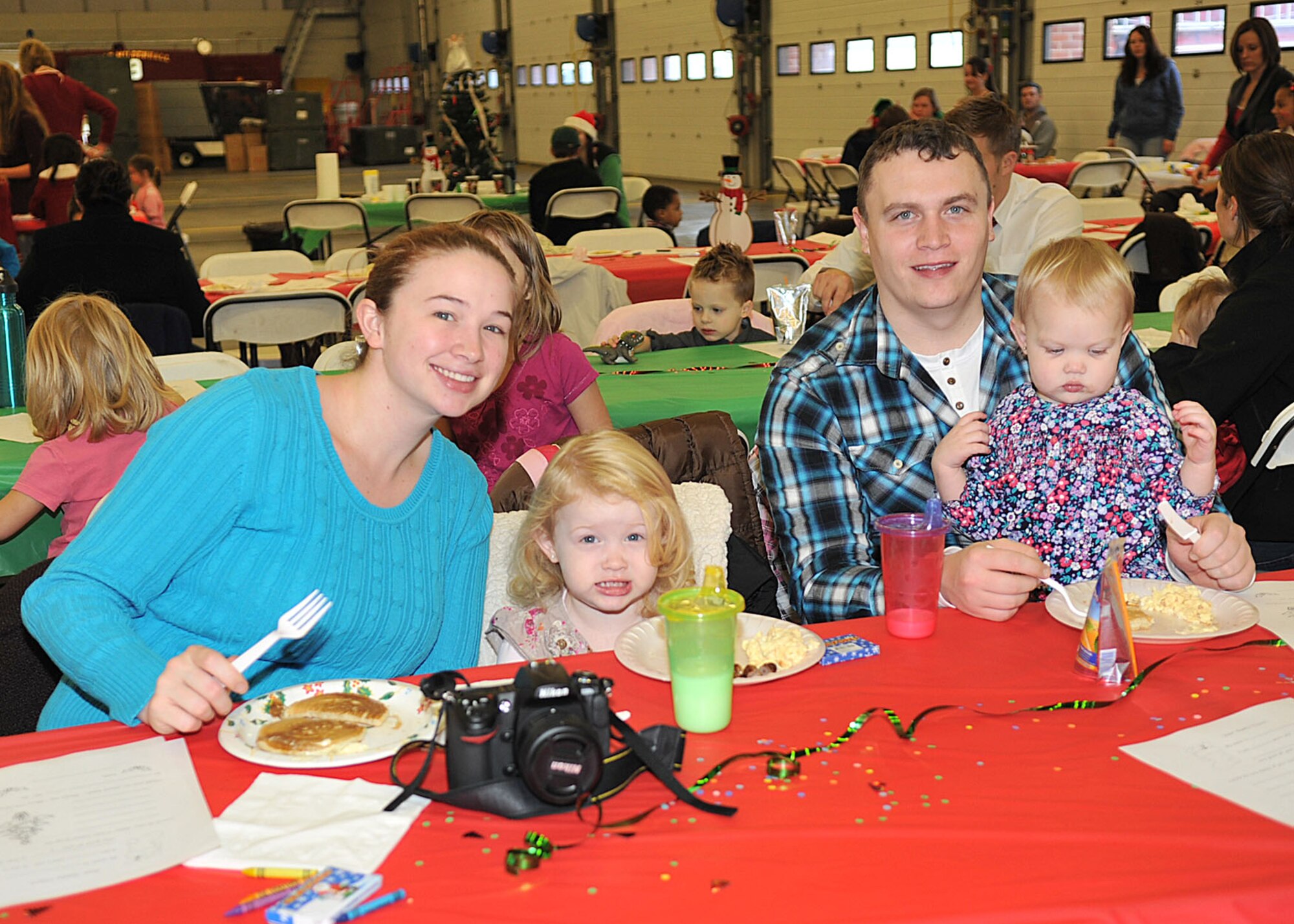 RAF MILDENHALL, England - Staff Sgt. John Bridges, 352nd Special Operations Group, wife, Leslie and daughters, Kaelyn, 3, and Layla, 19 months, stop to smile for a photo during the third annual Breakfast with Santa event at the fire department here Dec. 3, 2011. Volunteers prepared and served breakfast; the menu included pancakes, breakfast sausage, bacon and scrambled eggs. (U.S. Air Force photo/Senior Airman Jerilyn Quintanilla) 