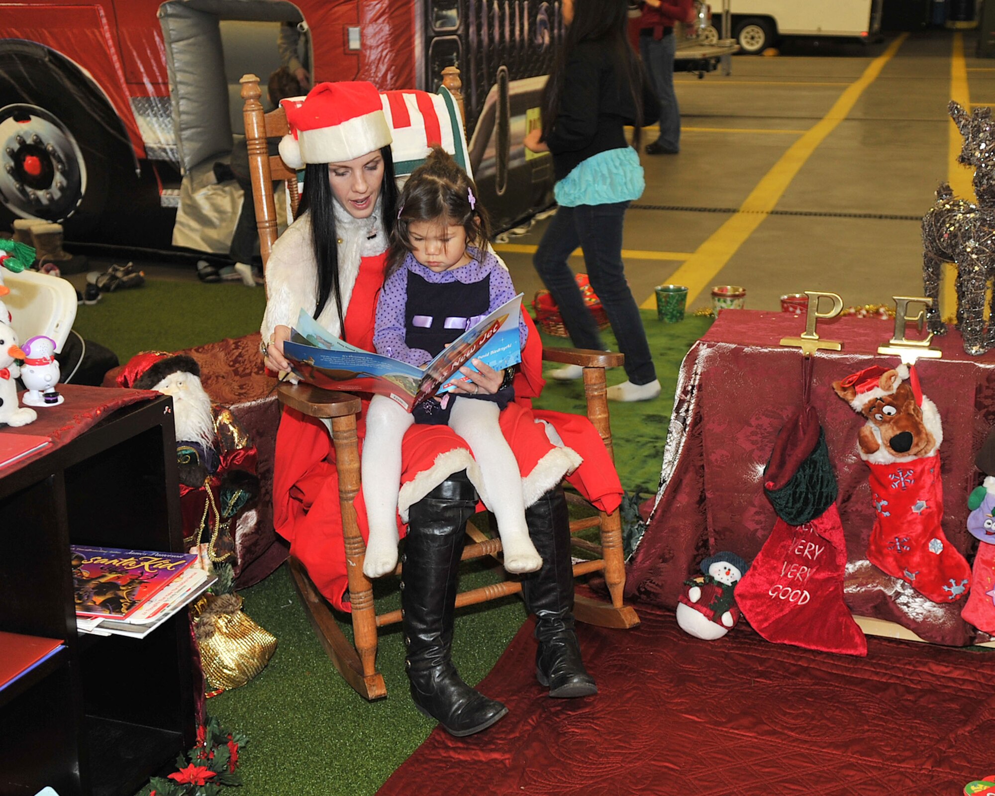 RAF MILDENHALL, England - JoEllen Treherne, a volunteer with the Officers and Civilians Spouses’ Club, reads to Adrianna Dumlao, 3, daughter of Staff Sgt. Danny Dumlao, at the third annual Breakfast with Santa event at the fire department here Dec. 3, 2011. Sponsored by the Officers and Civilians Spouses’ and Enlisted Spouses’ Clubs, the event was run entirely by volunteers, with more than 60 people showing up to lend a helping hand. (U.S. Air Force photo/Senior Airman Jerilyn Quintanilla)