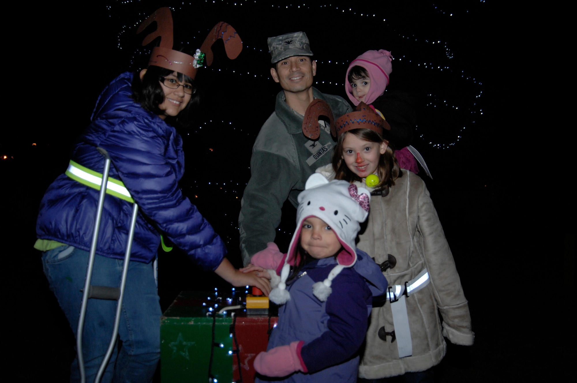 ROYAL AIR FORCE LAKENHEATH, England - Col. John Quintas, 48th Fighter Wing commander, lights the 48th FW Christmas tree with the help of Gwendolyn Stokes (left), Kaylan Jackson, and daughters Ava (center) and Elle, Dec. 2, 2011. The tree-lighting ceremony included caroling, cookies, hot chocolate and a visit from Santa Claus. (U.S. Air Force photo by Staff Sgt. David Dobrydney)