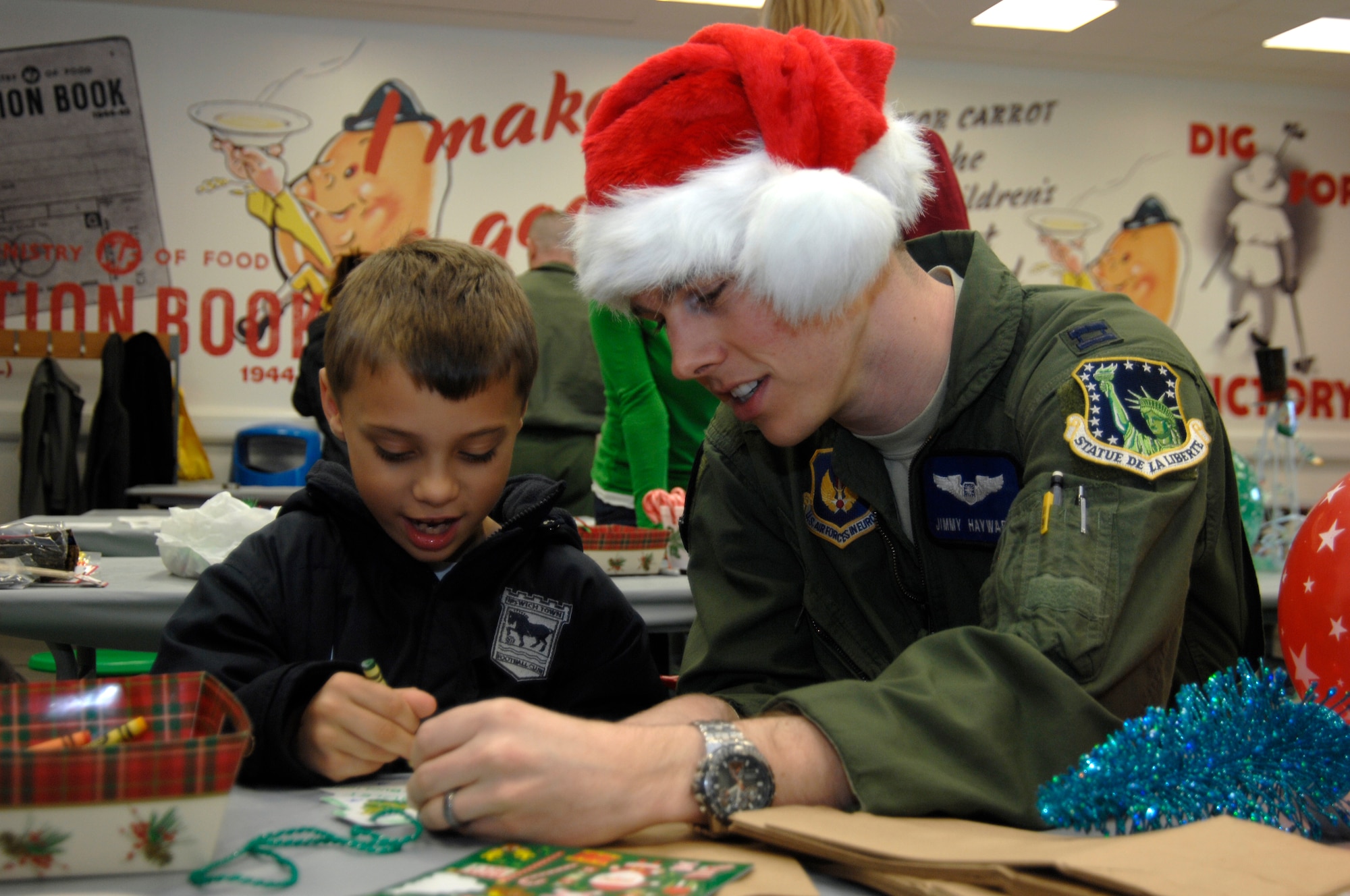DUXFORD IMPERIAL WAR MUSEUM, England - Capt. Jimmy Hayward, 492nd Fighter Squadron weapons systems officer, colors with Bradley Taylor-Buglione, 8, at the 492nd FS Christmas party, Dec. 3, 2011. The party was hosted for 50 children from U.K. hospitals and featured crafts, games, caroling and a visit from Santa Claus. (U.S. Air Force photo by Staff Sgt. David Dobrydney)