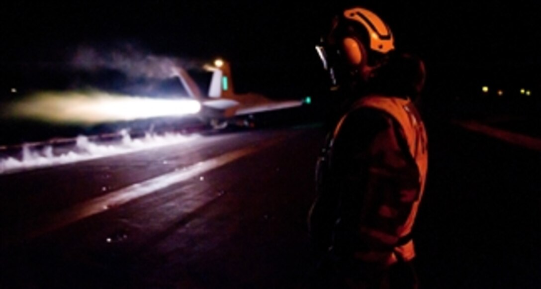A U.S. Navy sailor observes as an aircraft launches during night flight operations on the flight deck of the aircraft carrier USS John C. Stennis (CVN 74) in the Arabian Gulf on Dec. 3, 2011.  The Stennis is deployed to the U.S. 5th Fleet area of responsibility conducting maritime security operations and support missions as part of Operations Enduring Freedom and New Dawn.  
