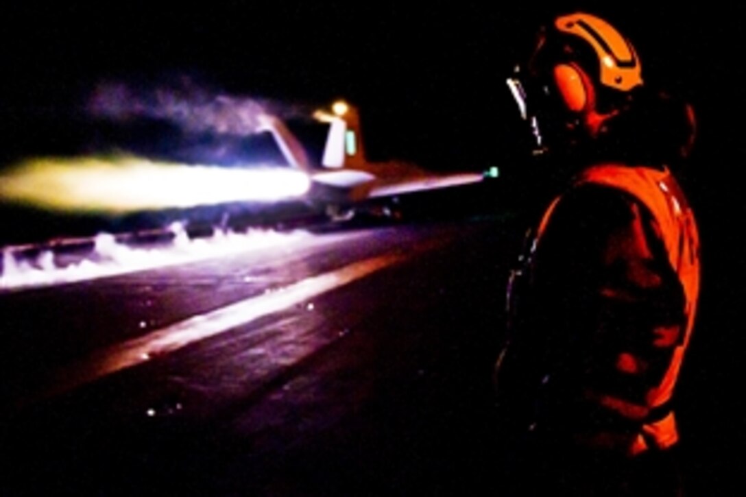 A U.S. Navy sailor observes as an aircraft launches during night flight operations on the flight deck of the aircraft carrier USS John C. Stennis in the Arabian Gulf, Dec. 3, 2011. The John C. Stennis is deployed to the U.S. 5th Fleet area of responsibility conducting maritime security operations and support missions as part of Operations Enduring Freedom and New Dawn.