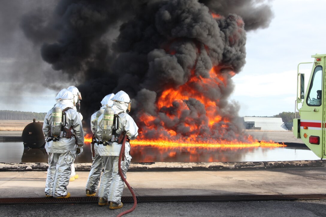 Aircraft Rescue and Firefighting Marines watch as a training fire builds intensity during a pit fuel fires training exercise at the burn pit Dec. 7. The Marines conduct this training during the day and night to better prepare them for real-life scenarios.