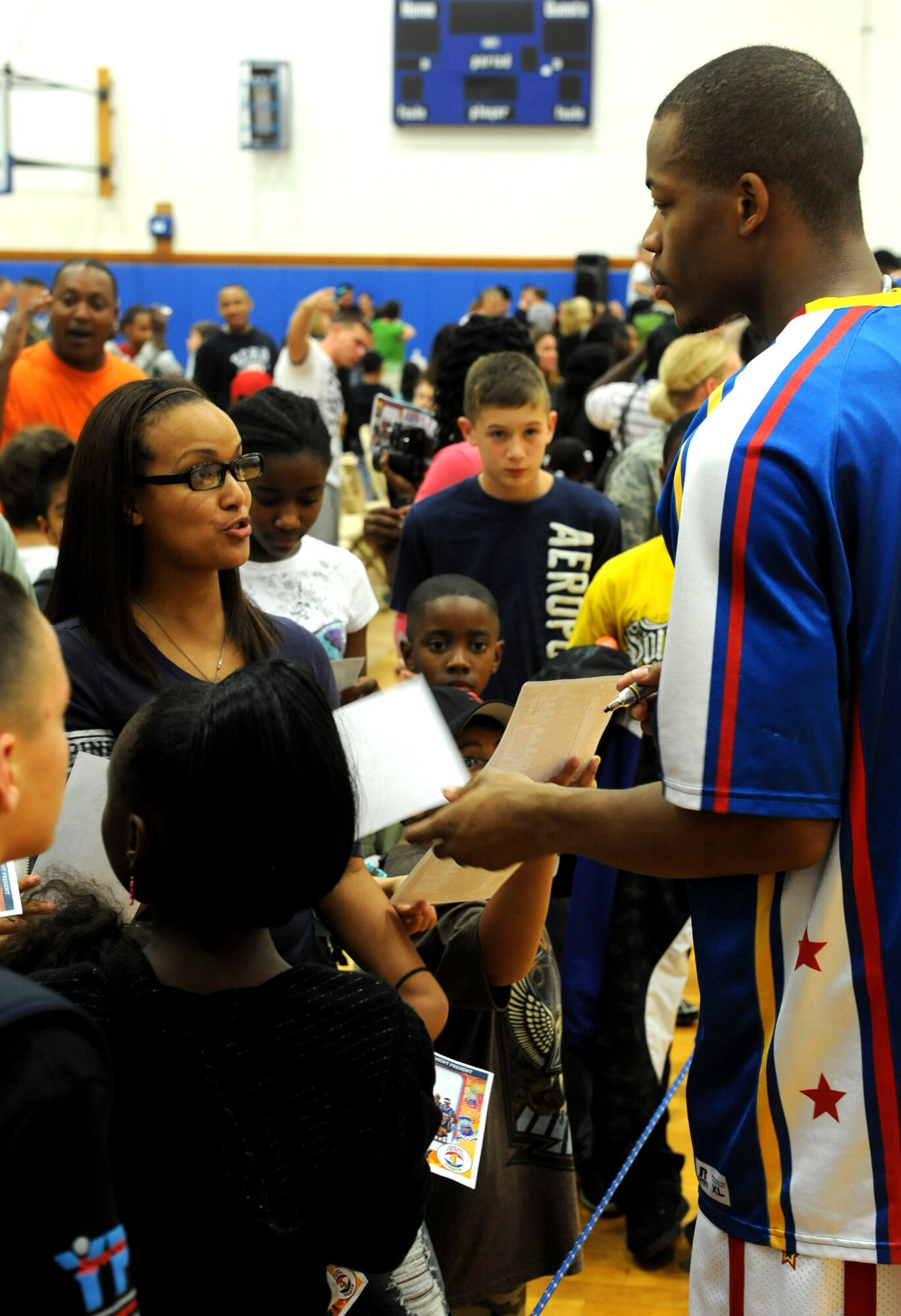 The Harlem Globetrotters' Hacksaw takes pictures and signs autographs at the end of their basketball game at the Risner gymnasium on Kadena Air Base, Japan, Dec. 6, 2011.The Harlem Globetrotters began in 1926 as the Savoy Big Five. Now more than 85 years and 20,000 games later, the team has become one of the most recognizable franchises in sports. (U.S. Air Force photo by Airman 1st Class Justin Veazie/Released)