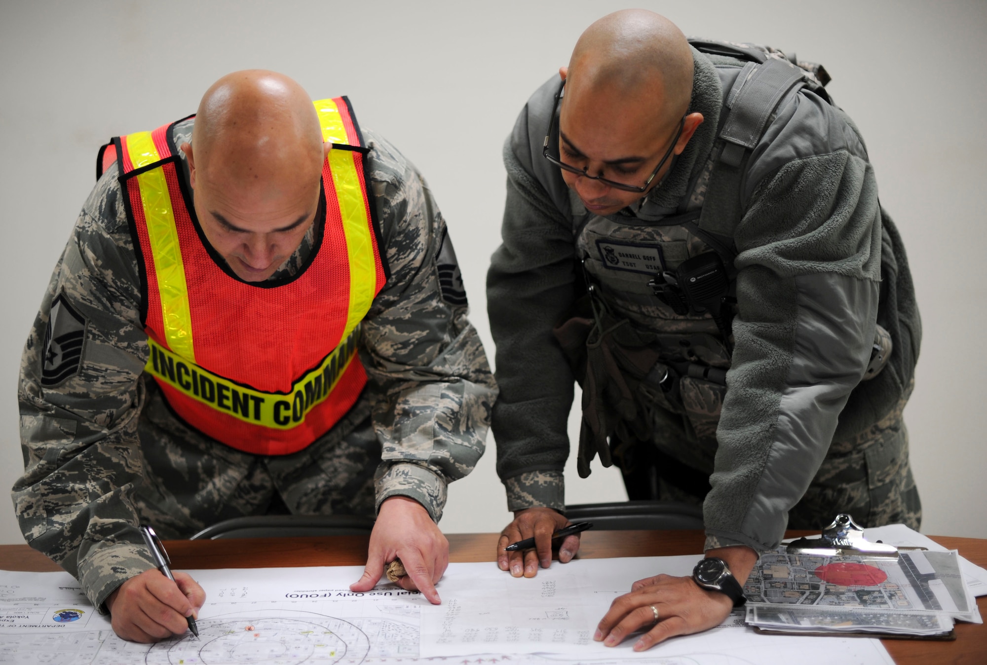 YOKOTA AIR BASE, Japan ? Master Sgt. James Beasly 374th Civil Engineering Squadron and Technical Sgt. Darrel Goff 374th Security Forces Squadron, work together at Yokota Air Base, Japan, 7 Dec. 2011. Both sergeants are planning coordination efforts to extend a preexisting cordon around a unexploded ordnance found near the fitness center, 6 Dec. 2011, to 1,500 feet. The device was determined to be a WWII-era bomb with an estimated explosive weight of 110 pounds.(U.S. Air Force Photo by/ Staff Sgt. Stacy Moless)