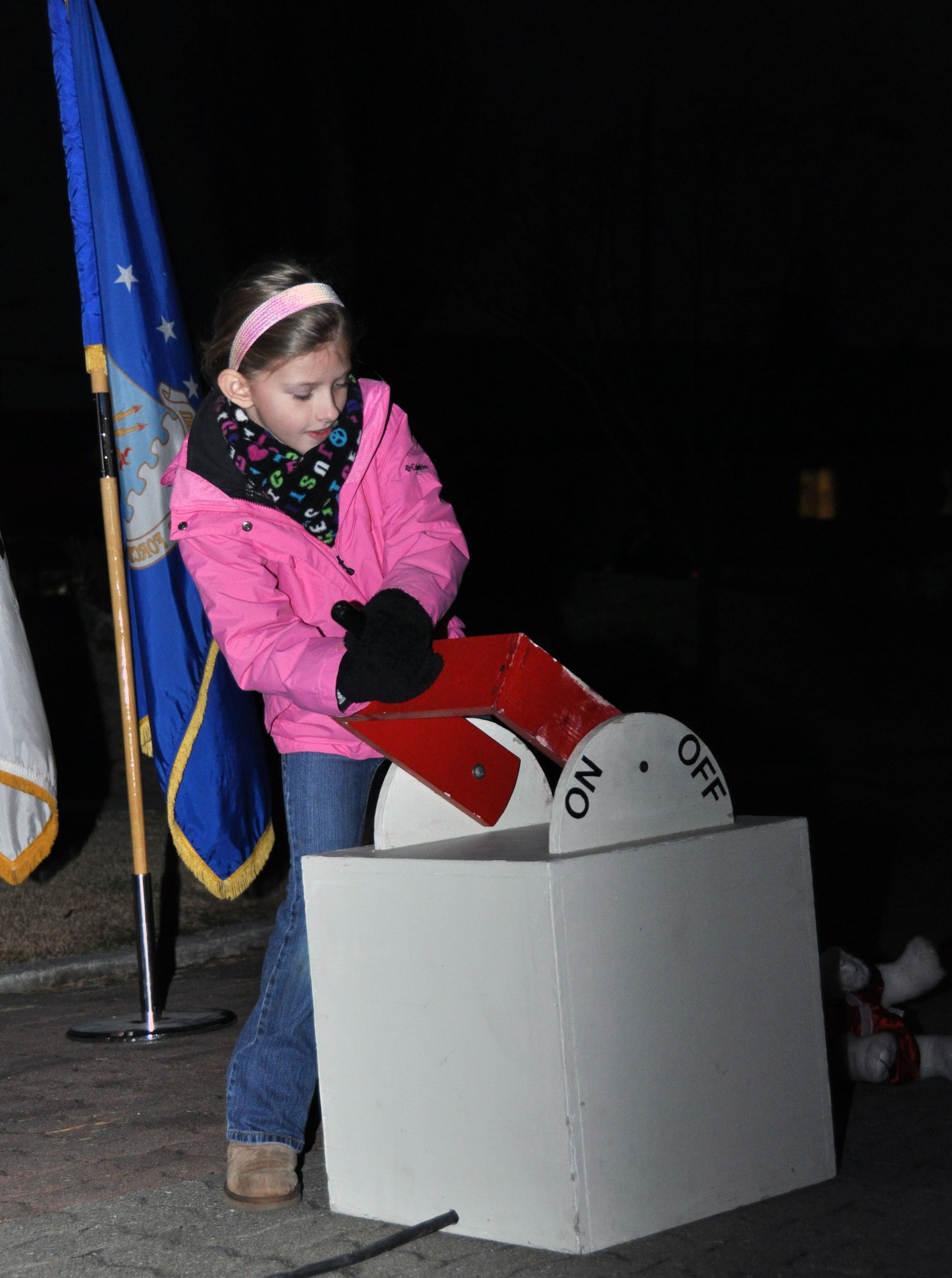 Ashley daughter of Col. Patrick McKenzie, 51st Fighter Wing commander, pulls the Christmas light switch during the base tree lighting ceremony Dec. 7, 2011. (U.S. Air Force photo/Airman 1st Class Michael Battles)